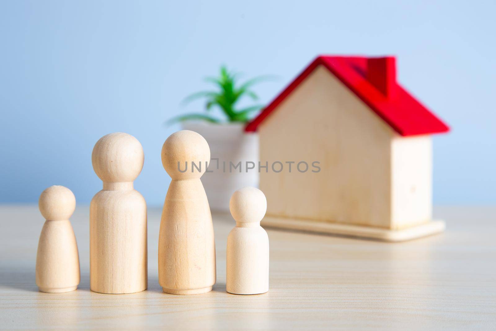 Wooden doll couple stands in front of house model. Family together protection and home insurance concept. by tehcheesiong