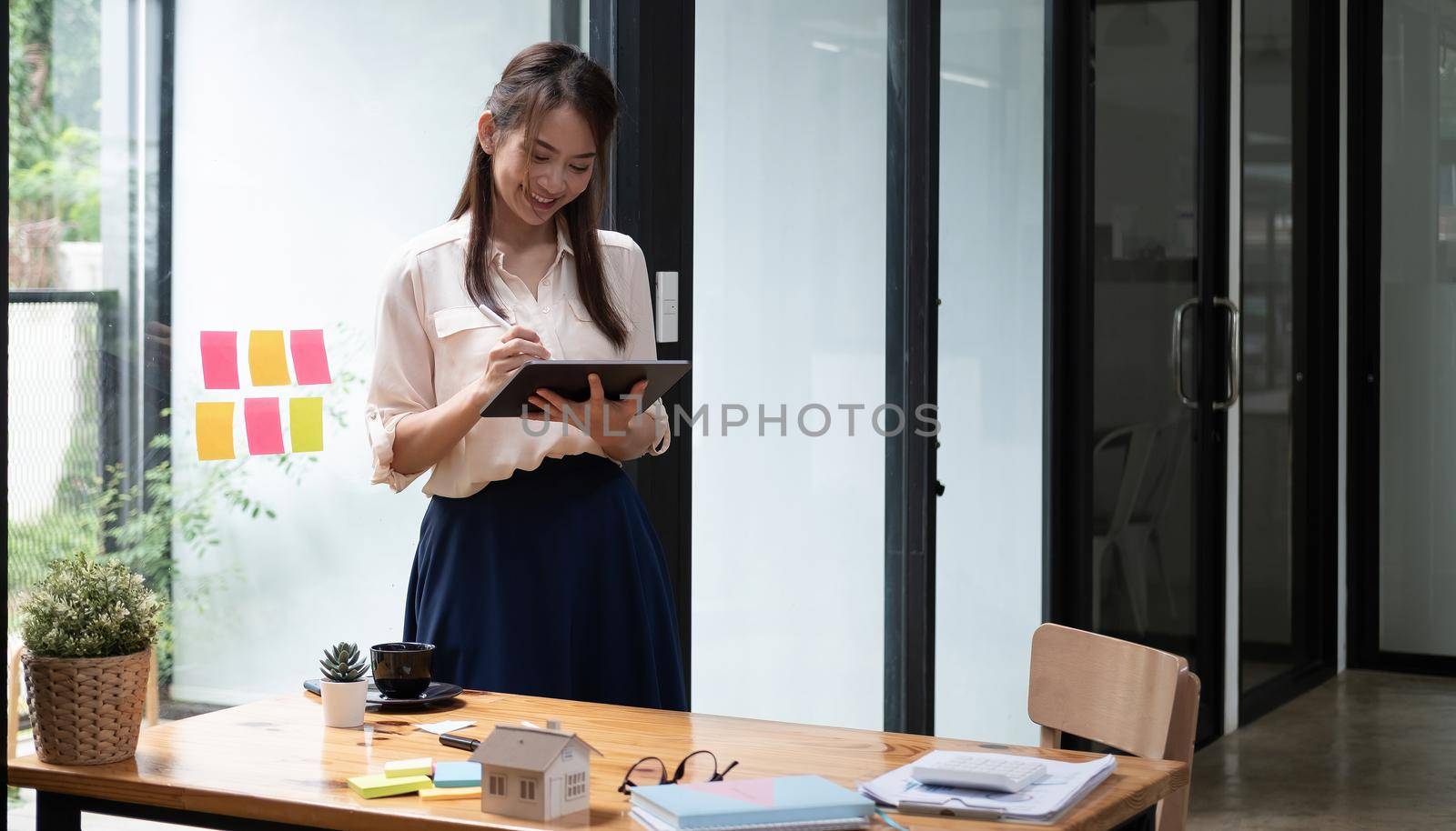 Happy woman manager holding tablet and standing in modern office. Asian female using stylus with tablet. business financial accounting concept.