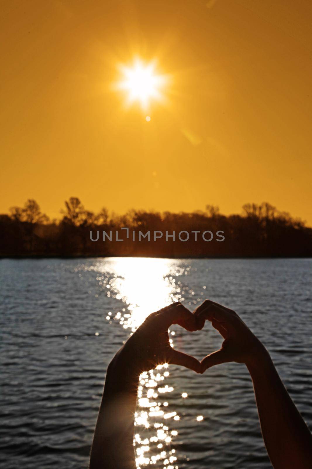 Hand shaped heart against sunset. Valentines day concept by Taut