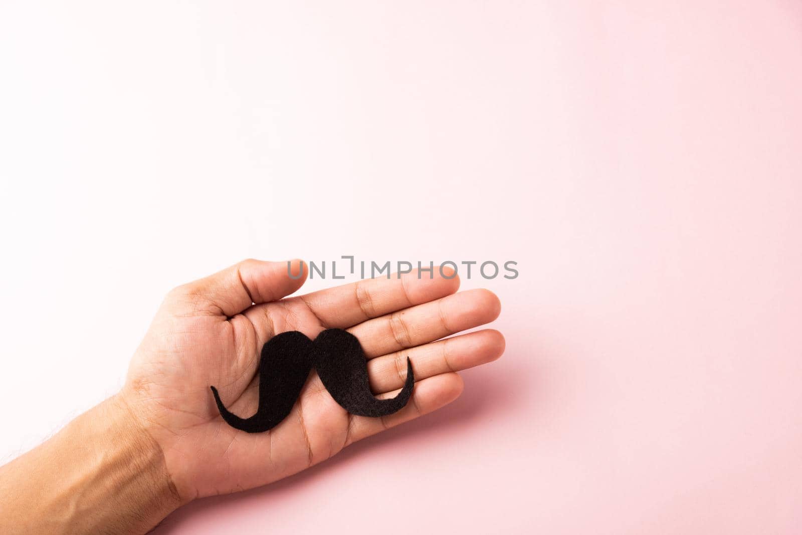 The man uses hand holding black mustache, studio shot isolated on white background, Prostate cancer awareness month, Fathers day, minimal November moustache concept