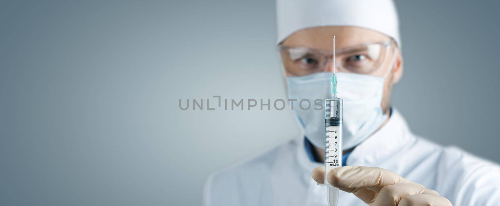 Doctor holding a syringe with vaccine against corona virus. by Taut