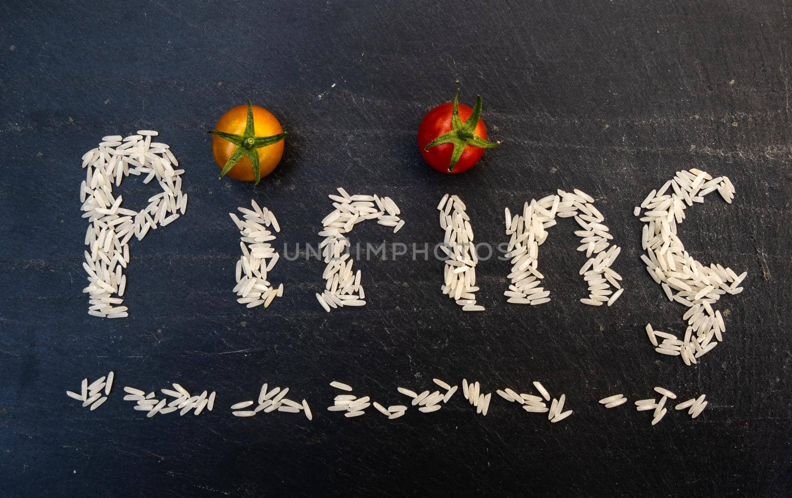 Turkish word pirinç written by white rice grains on a black slate board