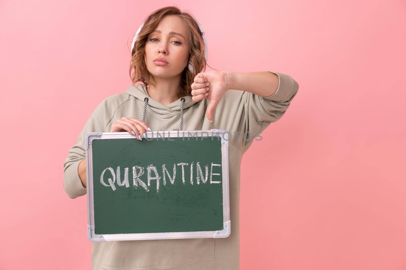 Stay home concept Woman with headphones dressed oversize hoodie holds chalkboard with the words quarantine. Coronavirus protection New normal concept Covid19 pandemic Social distancing work from home