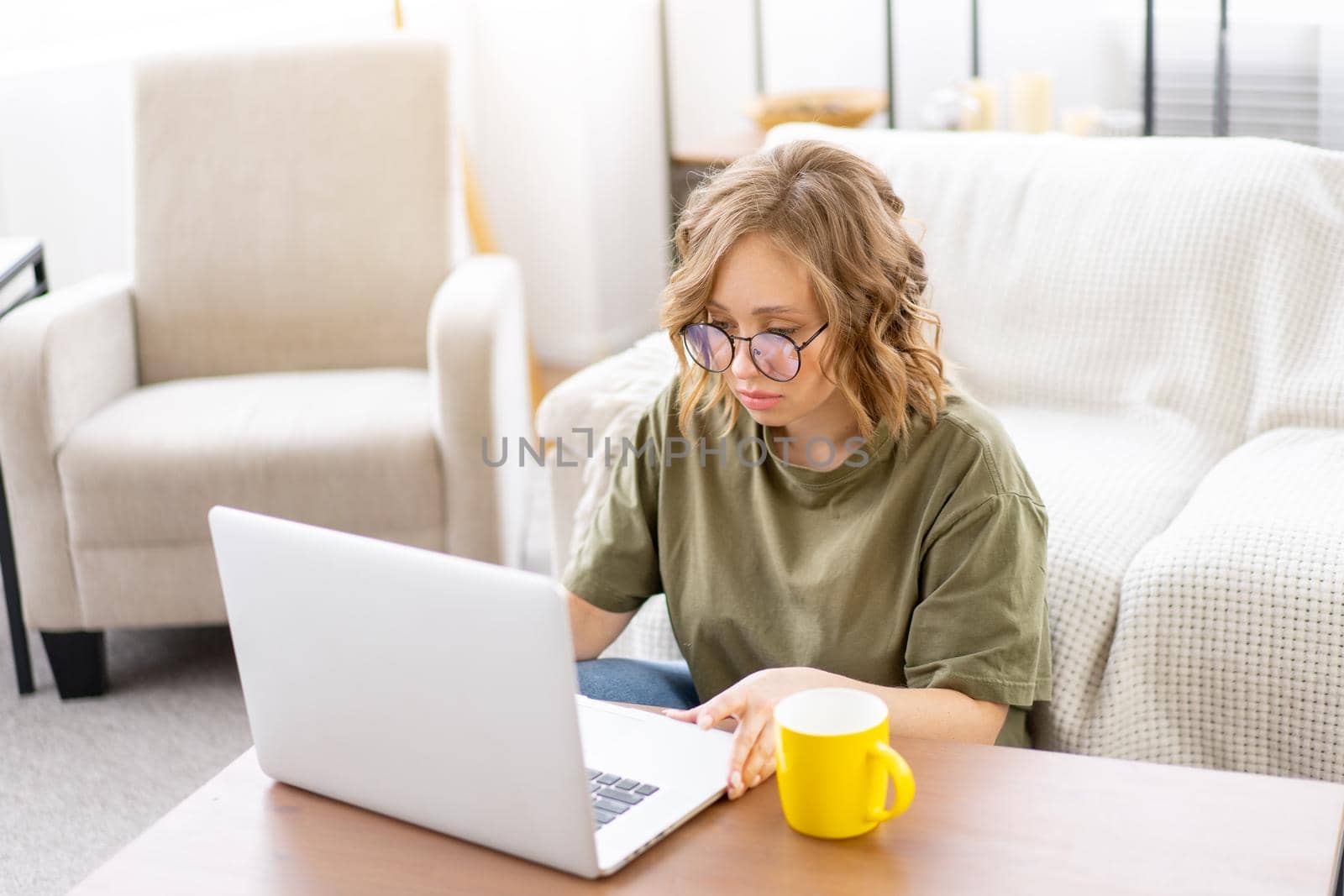 Woman with glasses use laptop drink morning coffee sitting floor near sofa big window background home interior Freelance female working home Distance learning student relaxing watch video lessons.