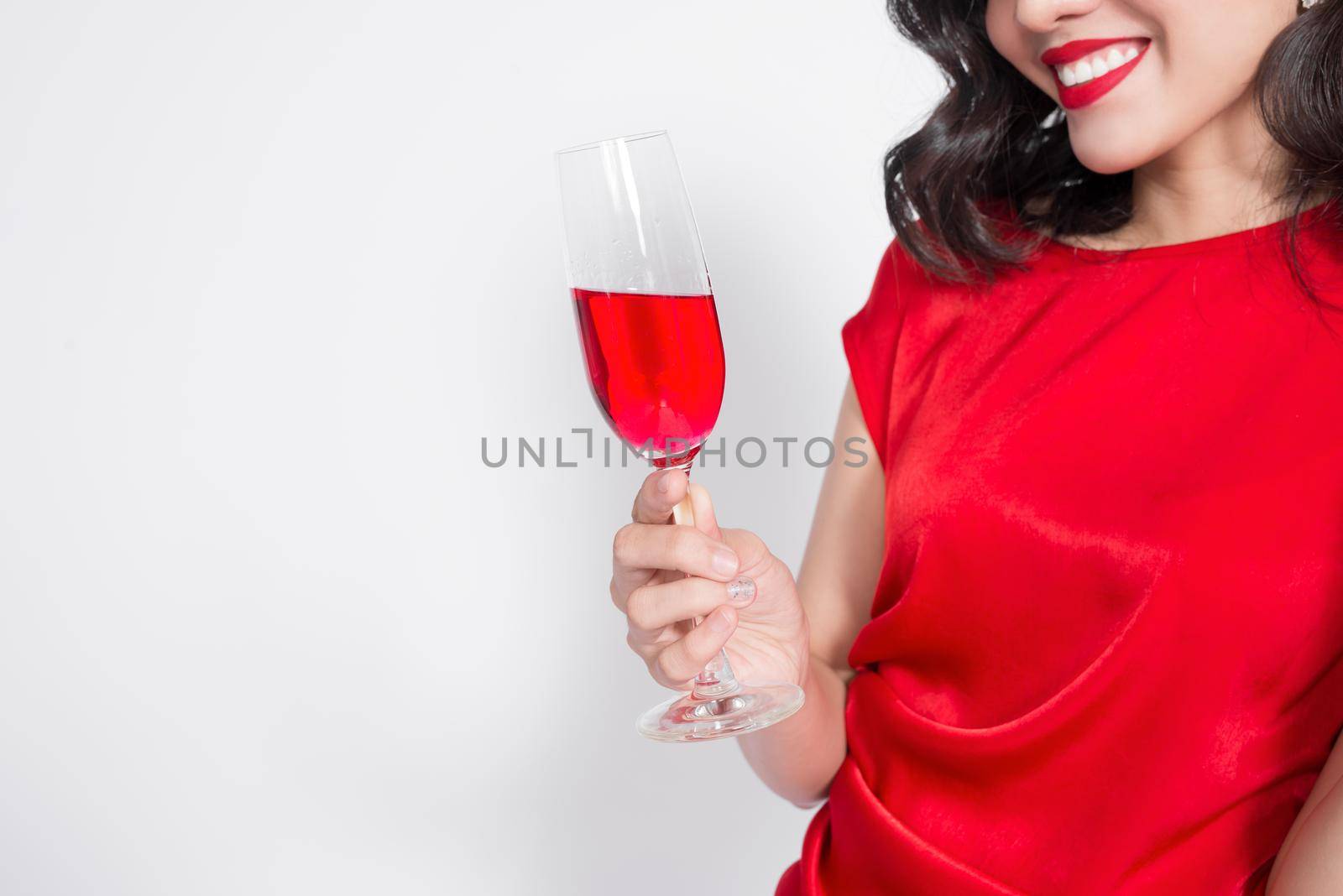 Cropped images of young celebrating asian woman in red dress holding wine glass.