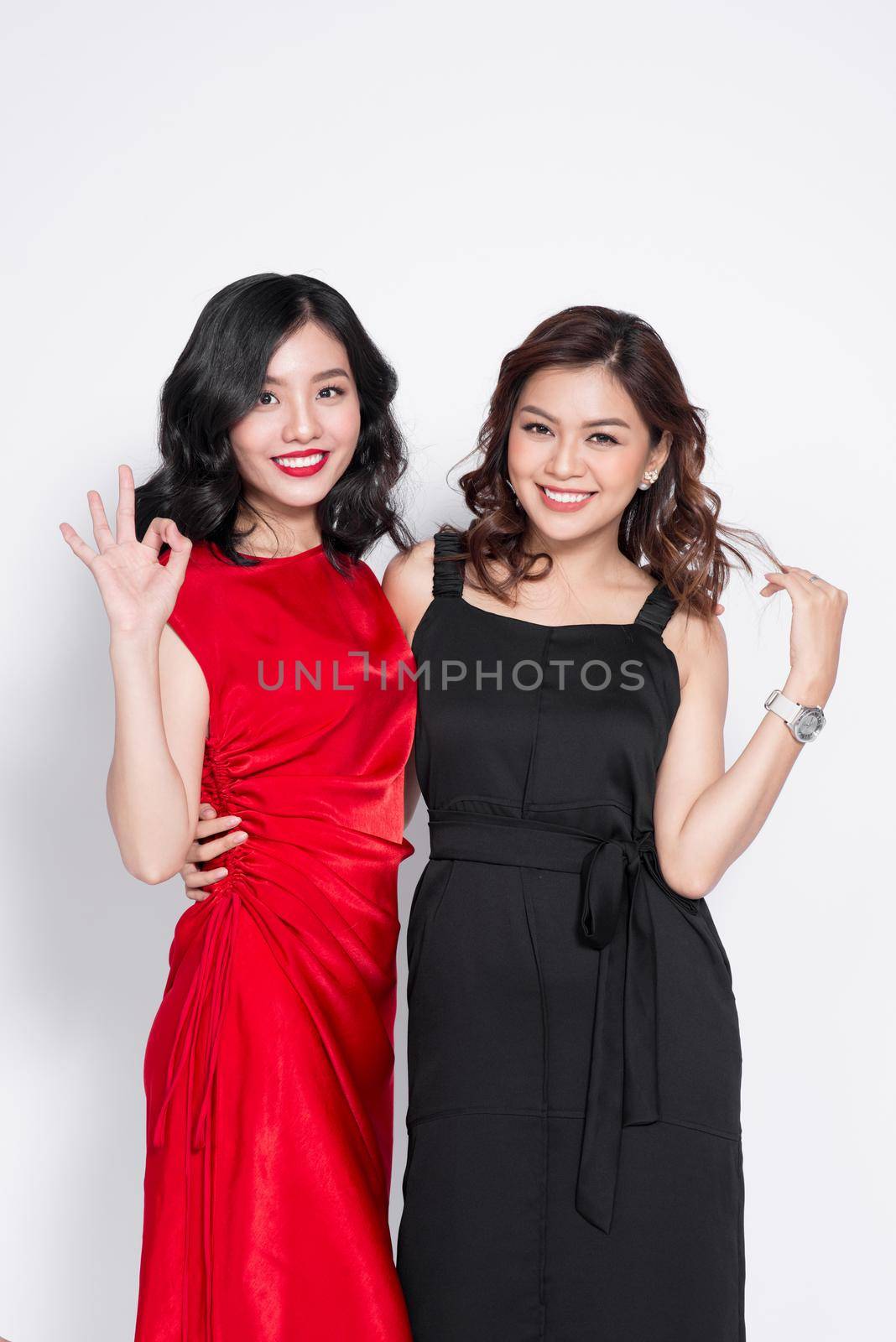 Two fashionable women in nice dresses standing together and having fun