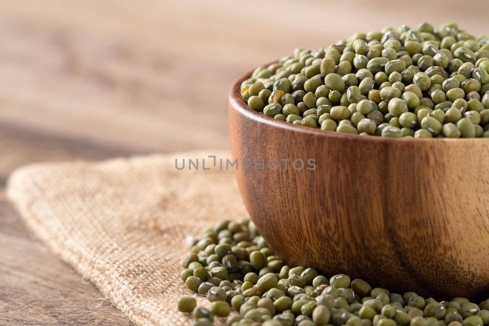 Close up of raw mung bean in a bowl on wooden table background.