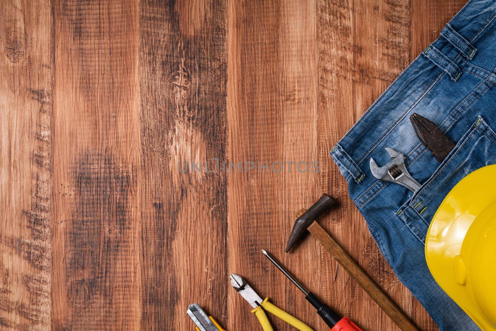 Top view design concept of Labor Day with working tools and jeans on wooden table background.