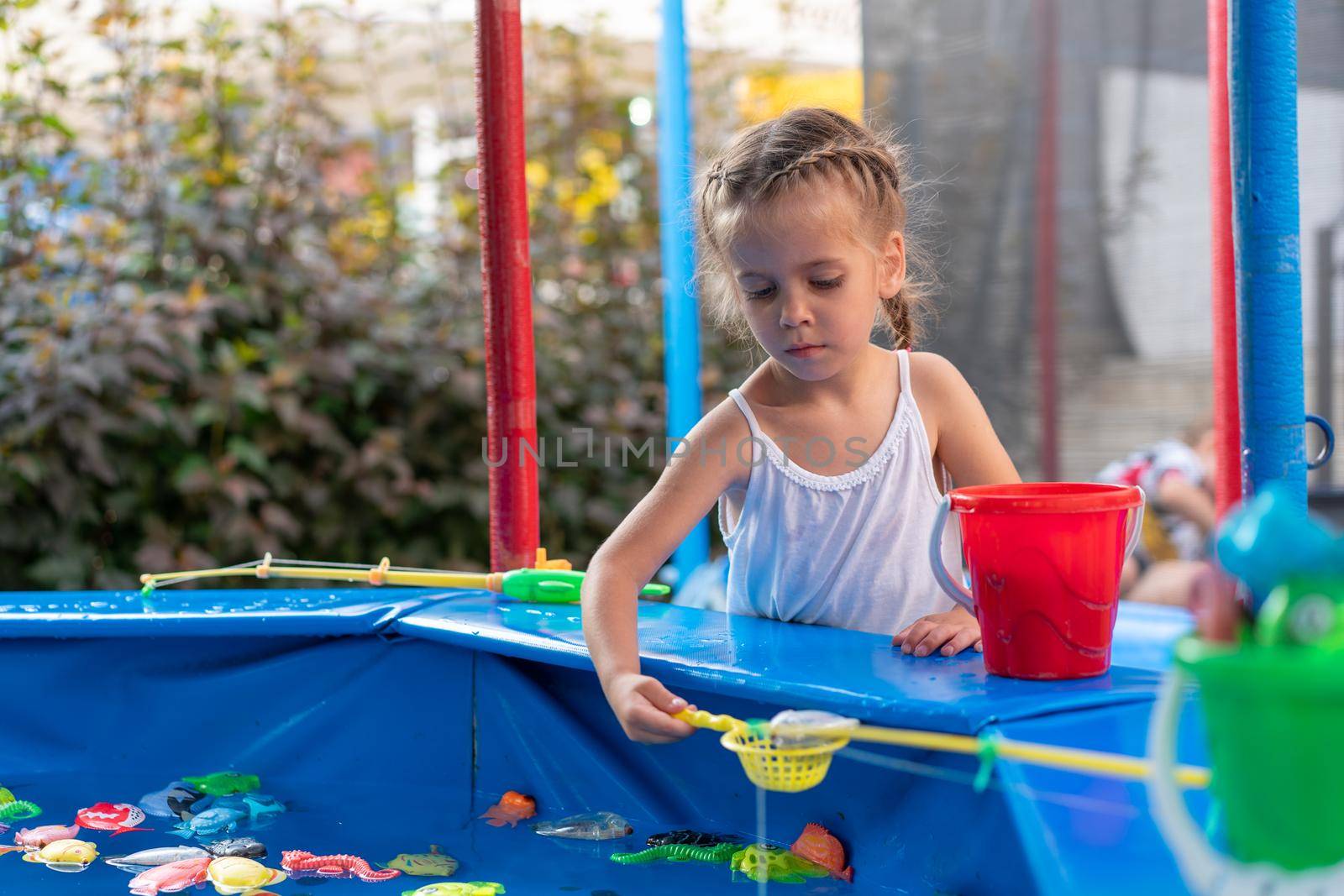 Child Fisher Catching Plastic Toy Fish On Pool Amusement Park Summer Day Little Girl Have Fun On Fishing Carnival Festival Entertainment For Children