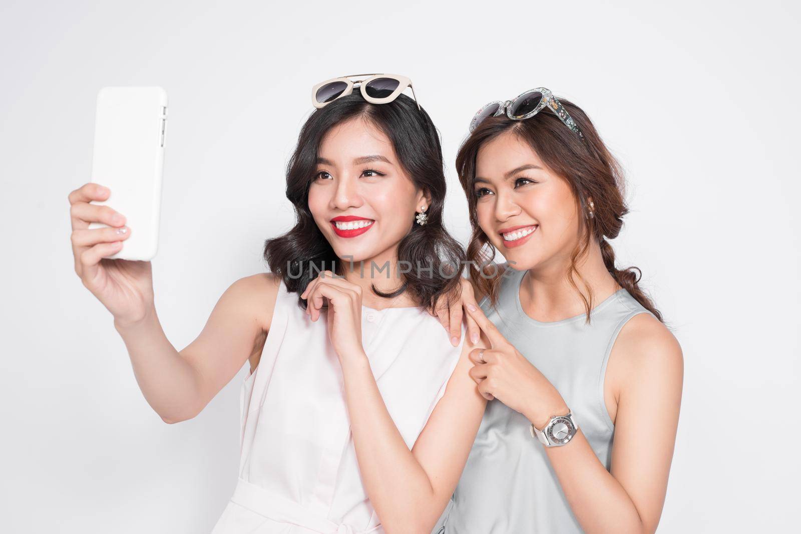 Portrait of two beautiful asian fashionable women taking selfie by makidotvn