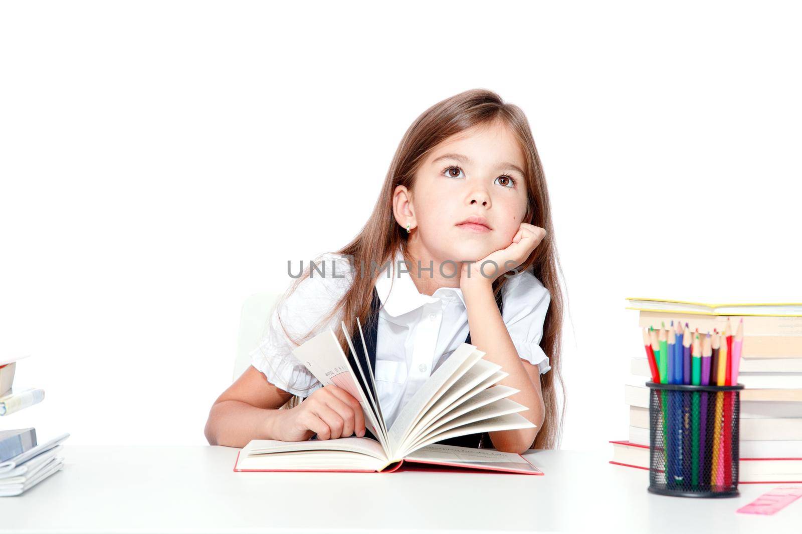 Cute little child girl looking up on the desk at school. by Taut