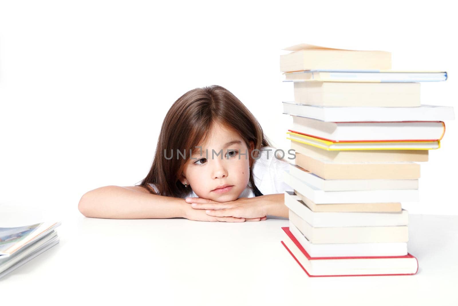 Young cute girl sitting at the table and reading a book by Taut