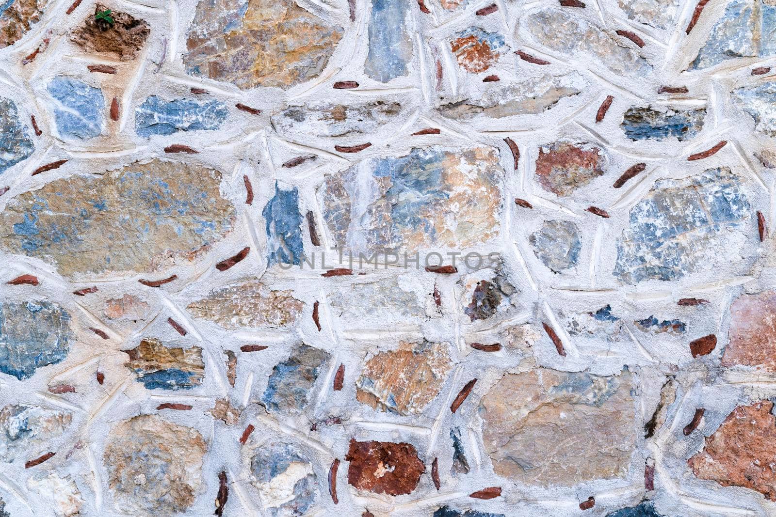 Texture of asymmetric masonry made of multicolored stones. Top view.