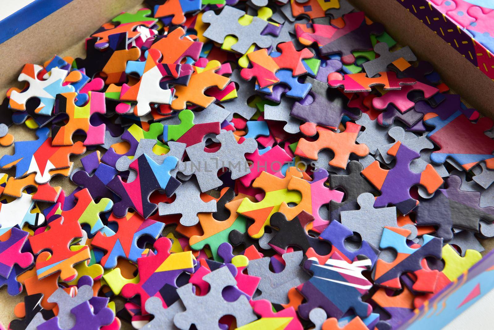 closeup heap of colorful jigsaw puzzle game in a box.