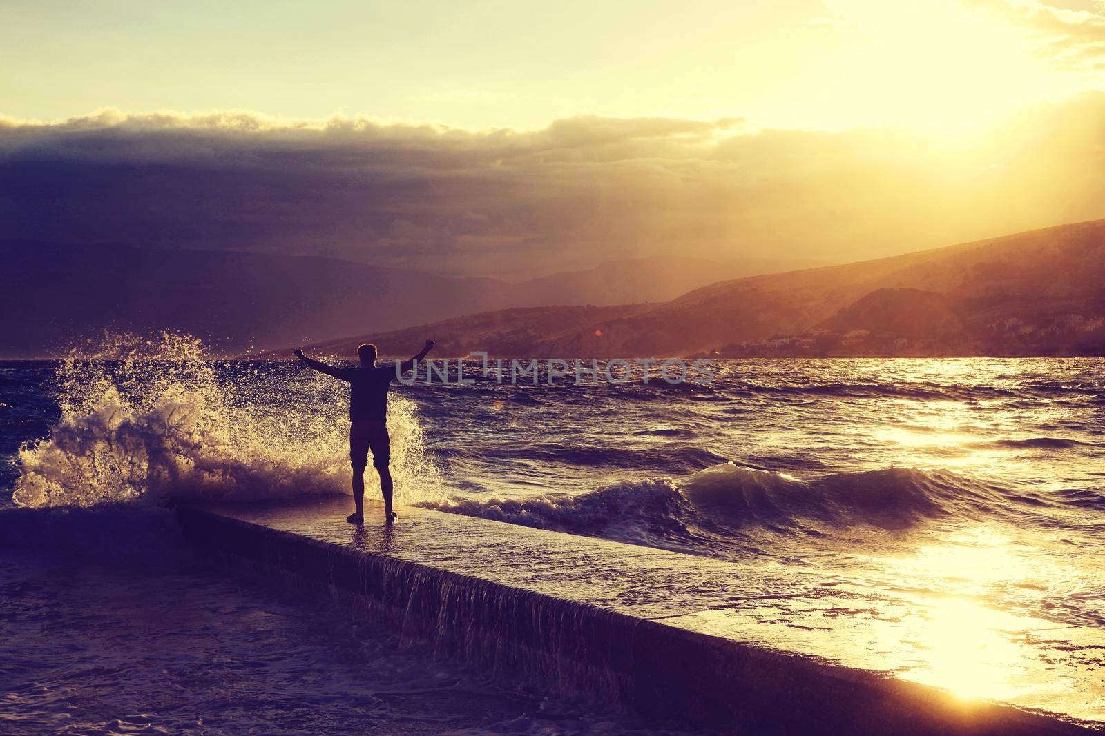 Feeling of freedom concept. Man standing on pier facing to the sea with big waves.