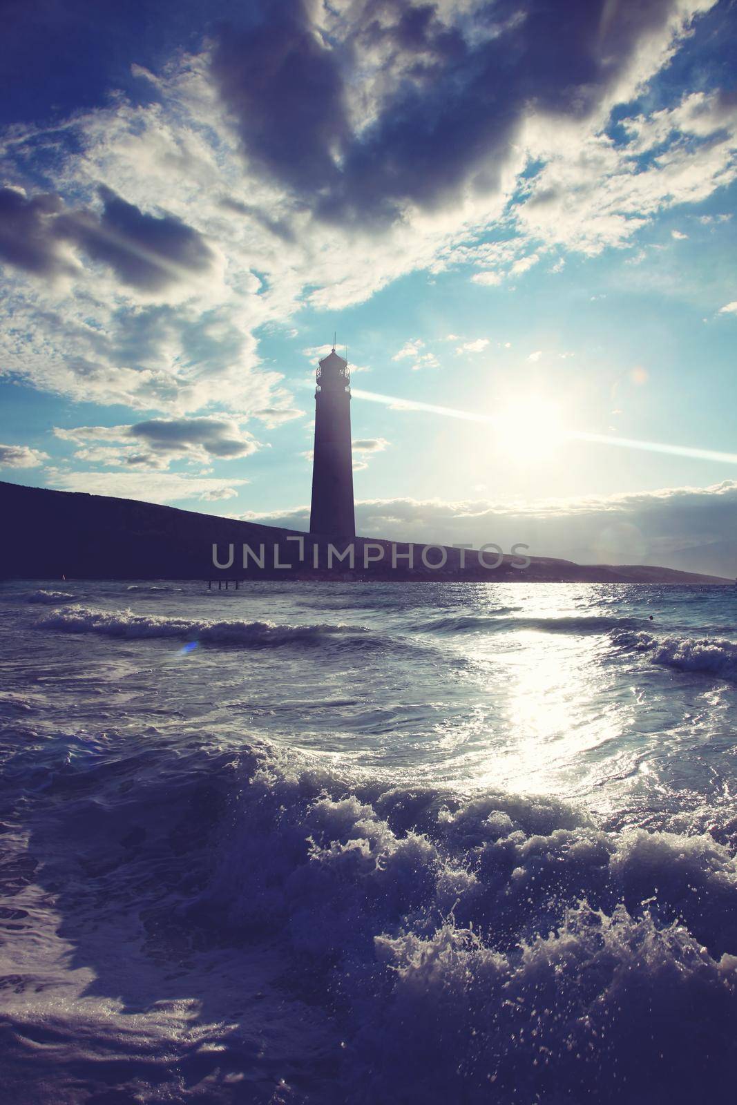 Old lighthouse searchlight beam through marine air. by Taut