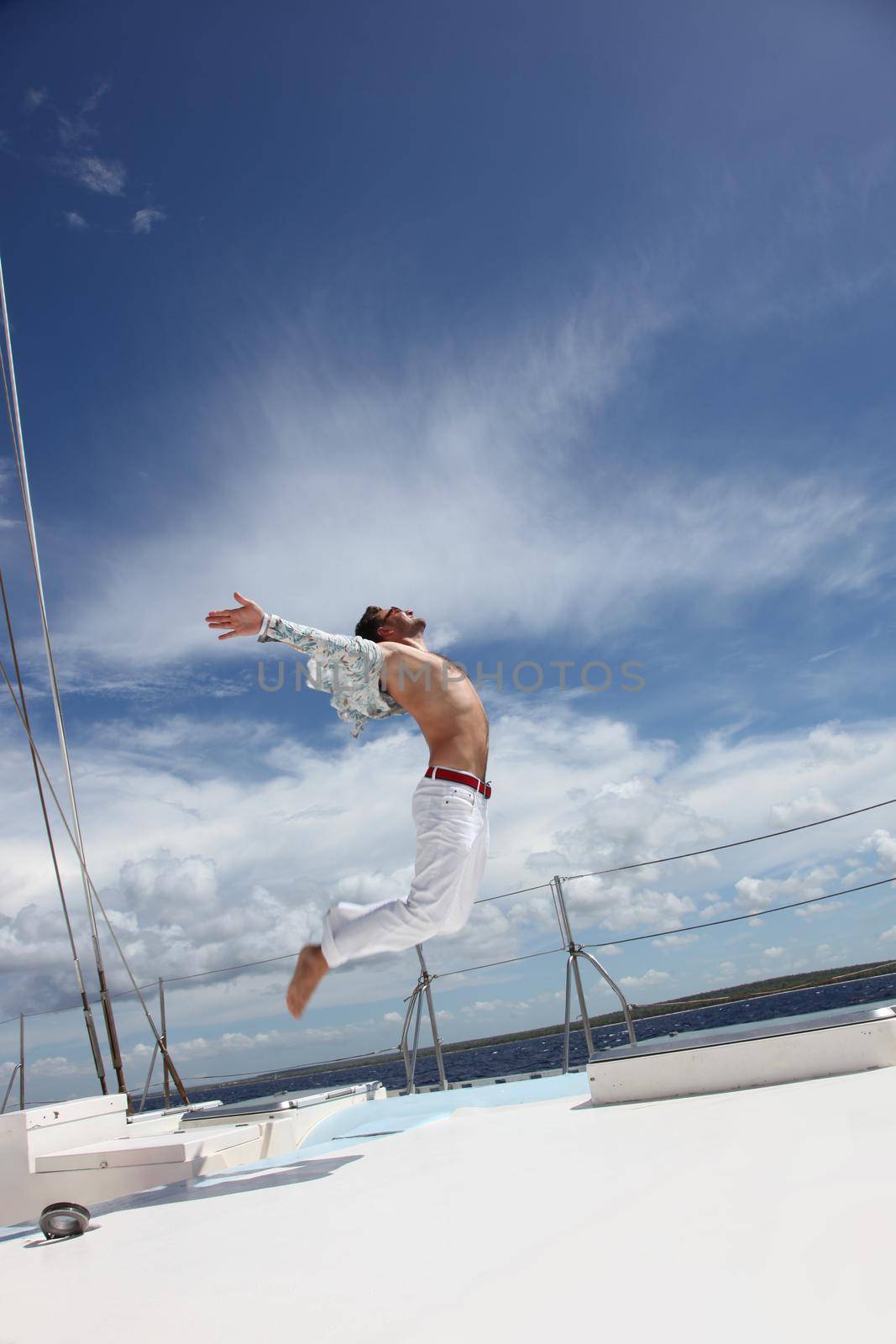 Young man sailing his boat on the open ocean by Taut