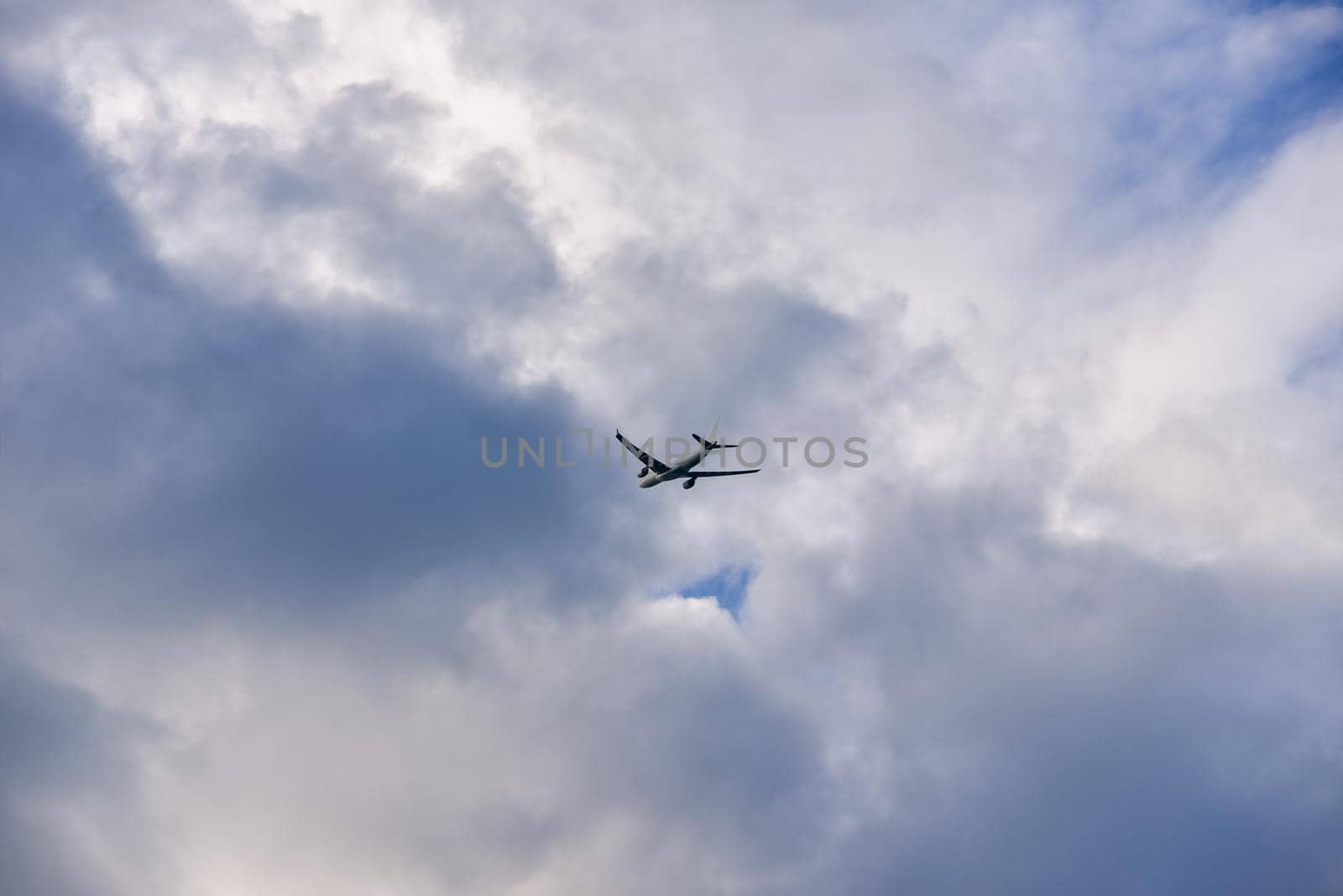 Passenger airplane is flying far away against the sky with clouds.