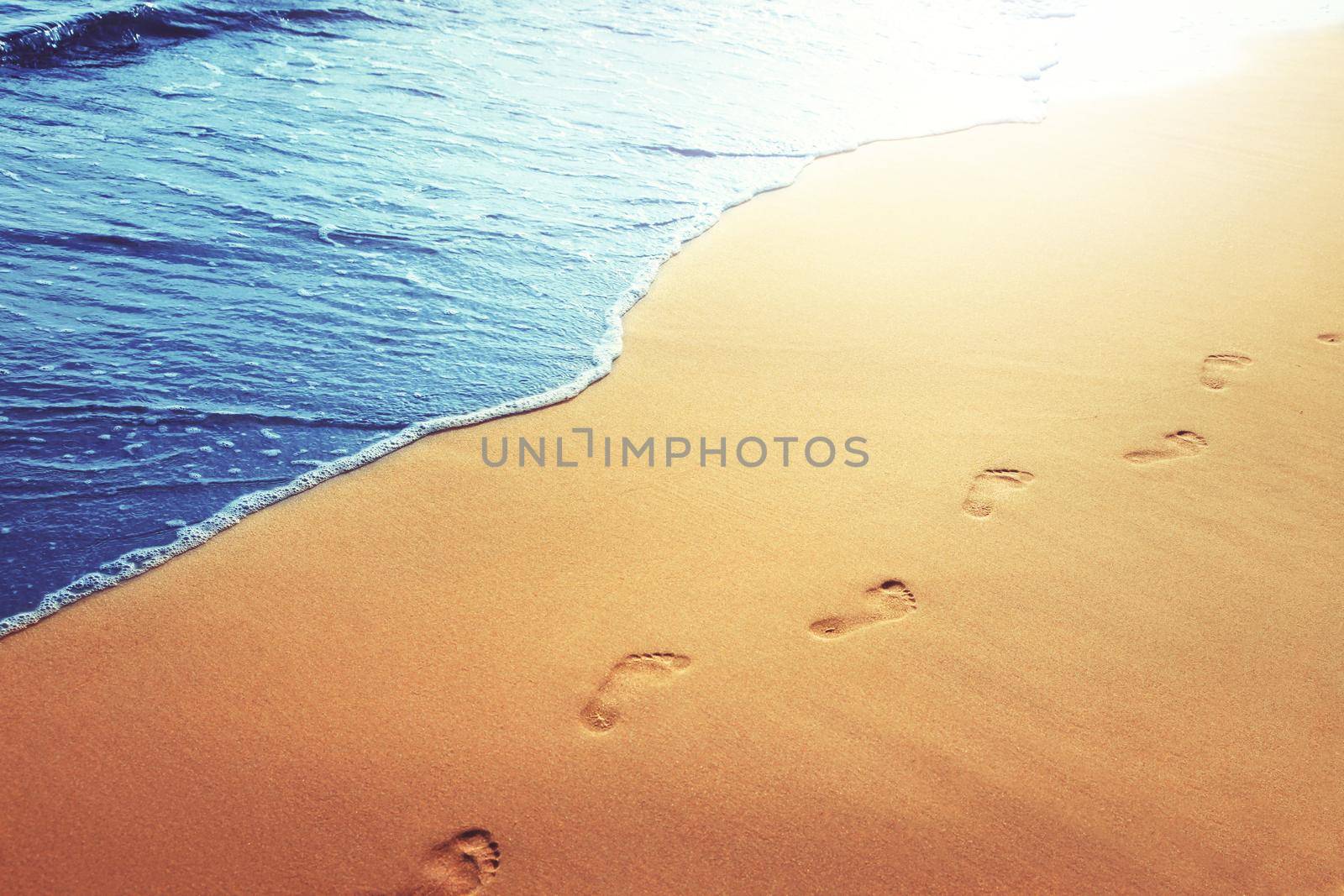 Detail of human feet in the golden sand at the beach. Summer travel and vacation concept.