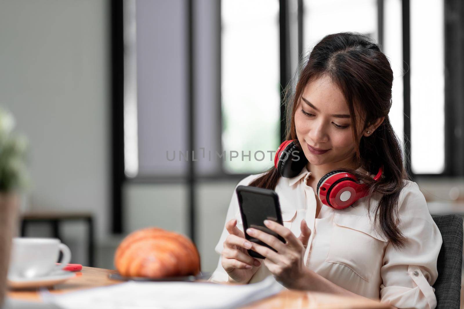 Asian woman wearing headphone while using of smart phonefor online meeting video call.