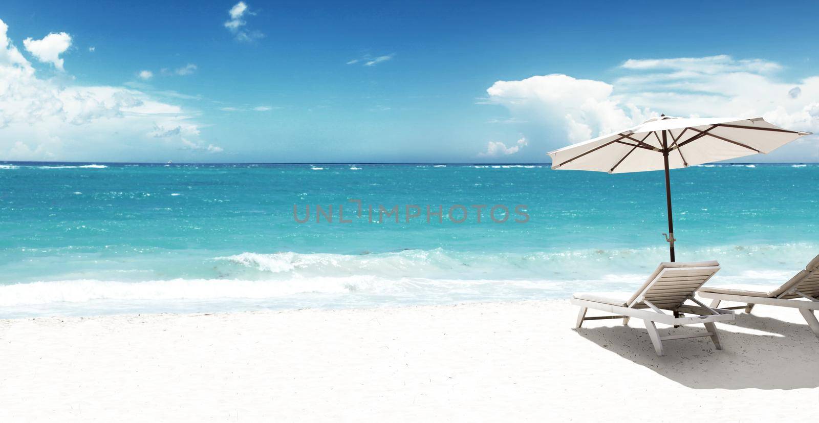 Wooden deck chairs on sandy beach near sea. Holiday background.