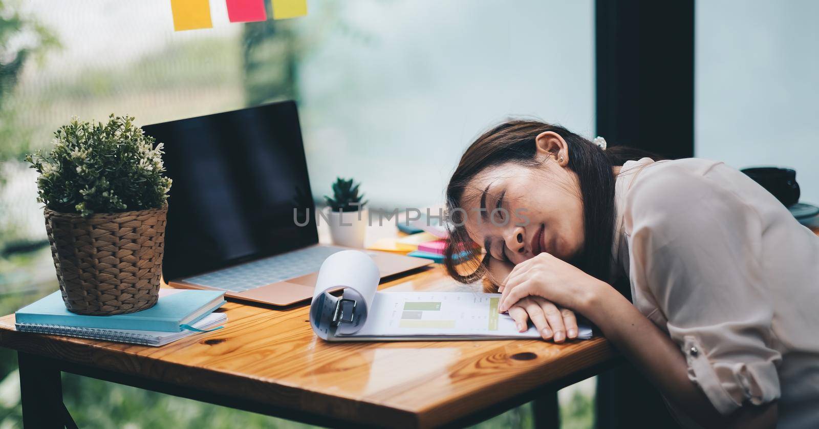 Tired and overworked business woman. Young exhausted girl sleeping on table during her work Entrepreneur, freelance worker in stress concept.