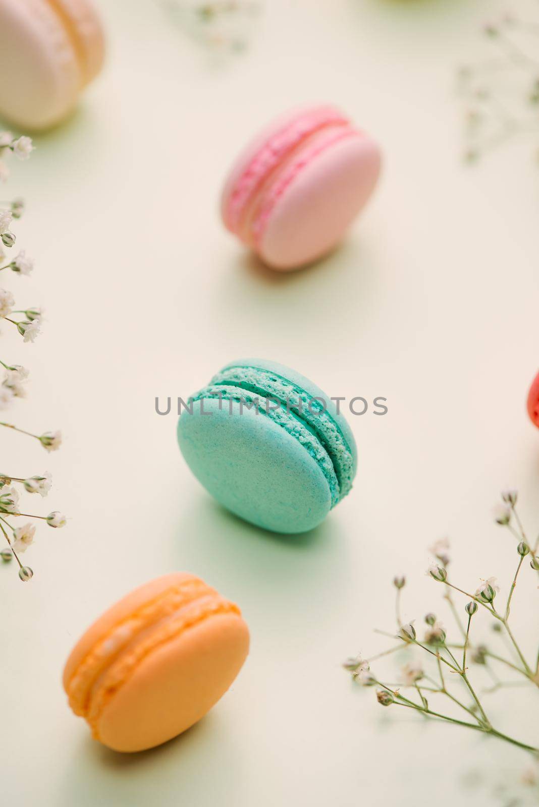Morning cake macaron and flower gypsophila on light green background from above. Cozy breakfast. Flat lay style.