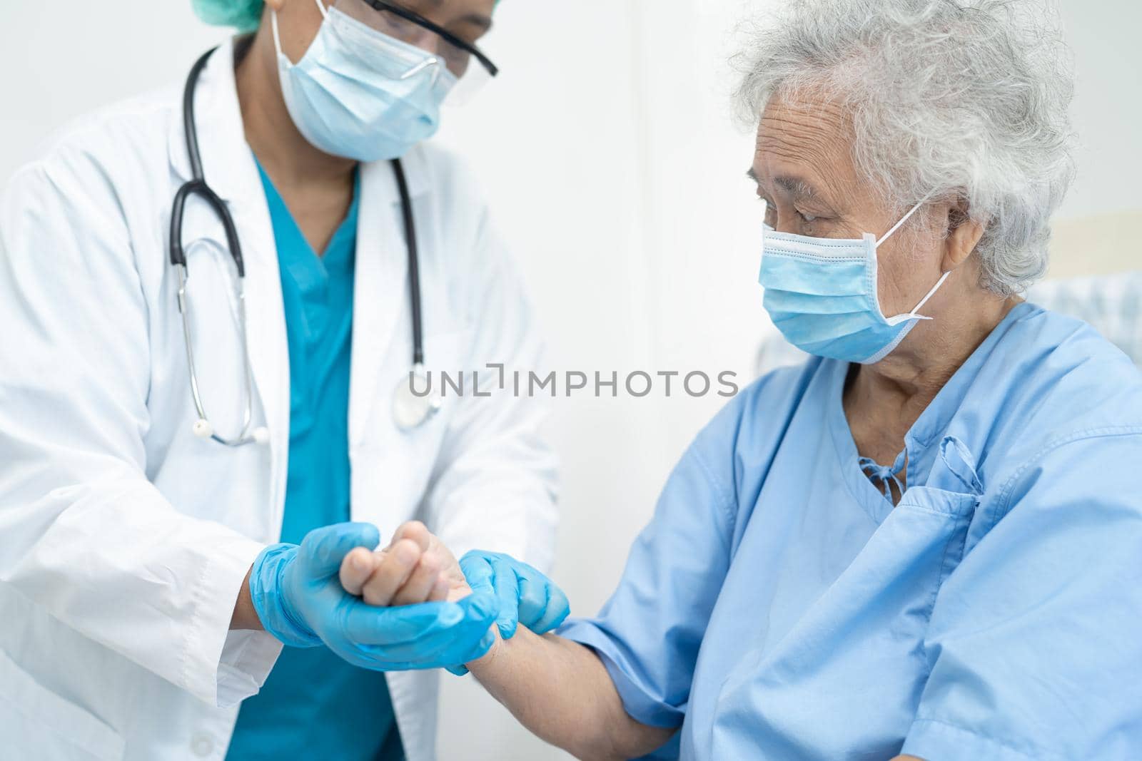 Doctor help Asian senior or elderly old lady woman patient wearing a face mask in hospital for protect safety infection and kill Covid-19 Coronavirus.