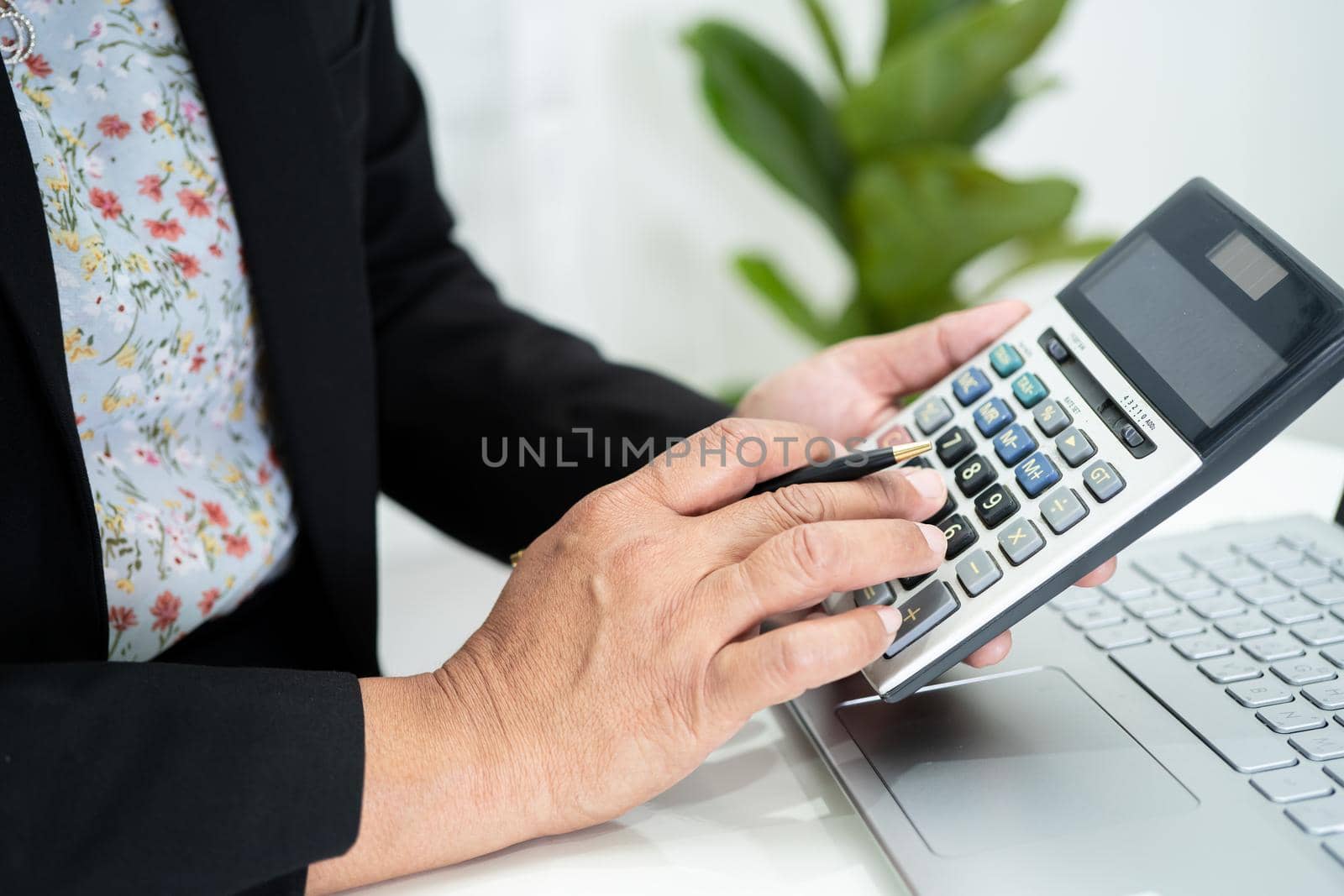 Asian accountant working and analyzing financial reports project accounting with labtop and calculator in modern office, finance and business concept.