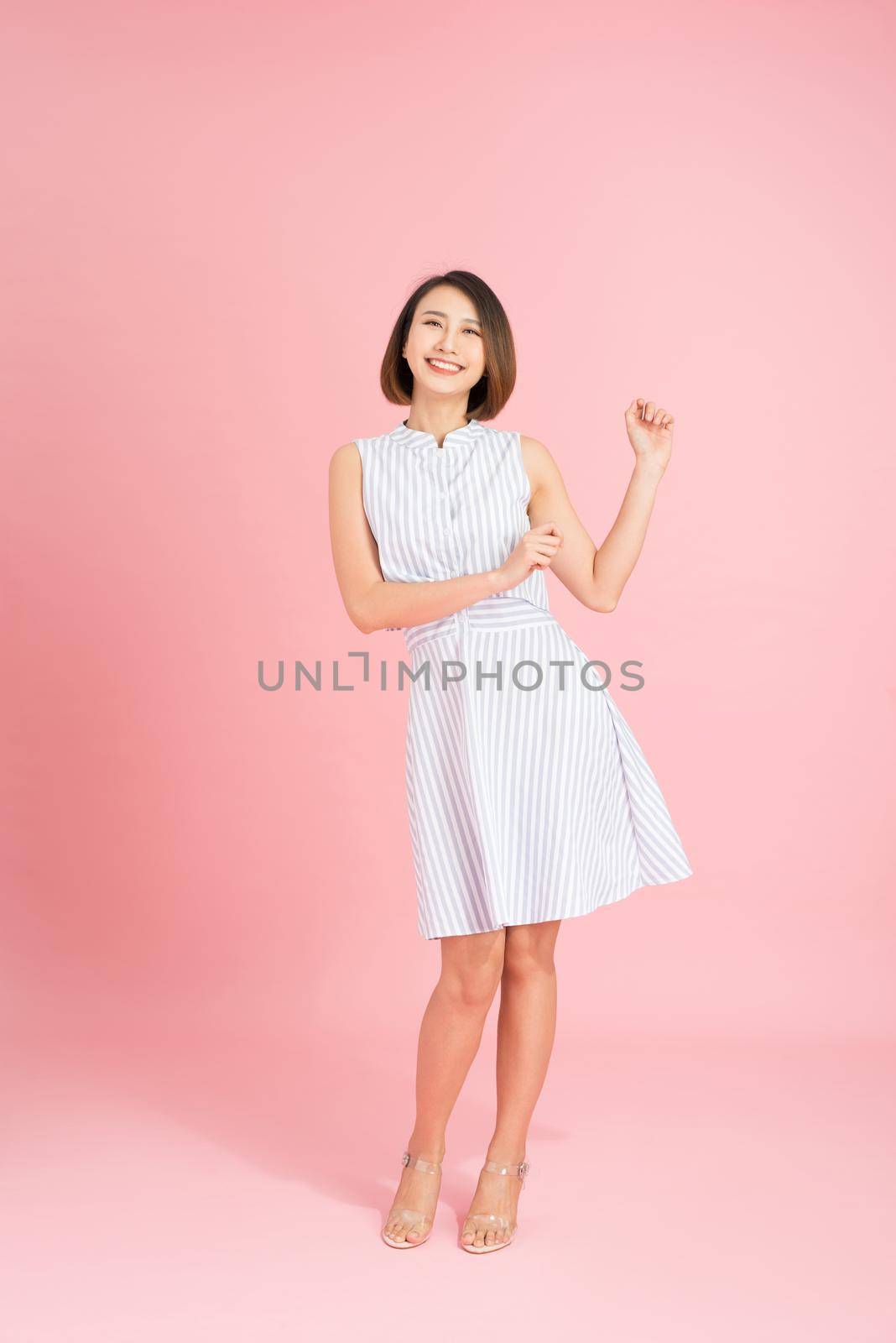 Young asian girl dancing with inspired face expression. Active young woman in casual summer outfit having fun indoor.