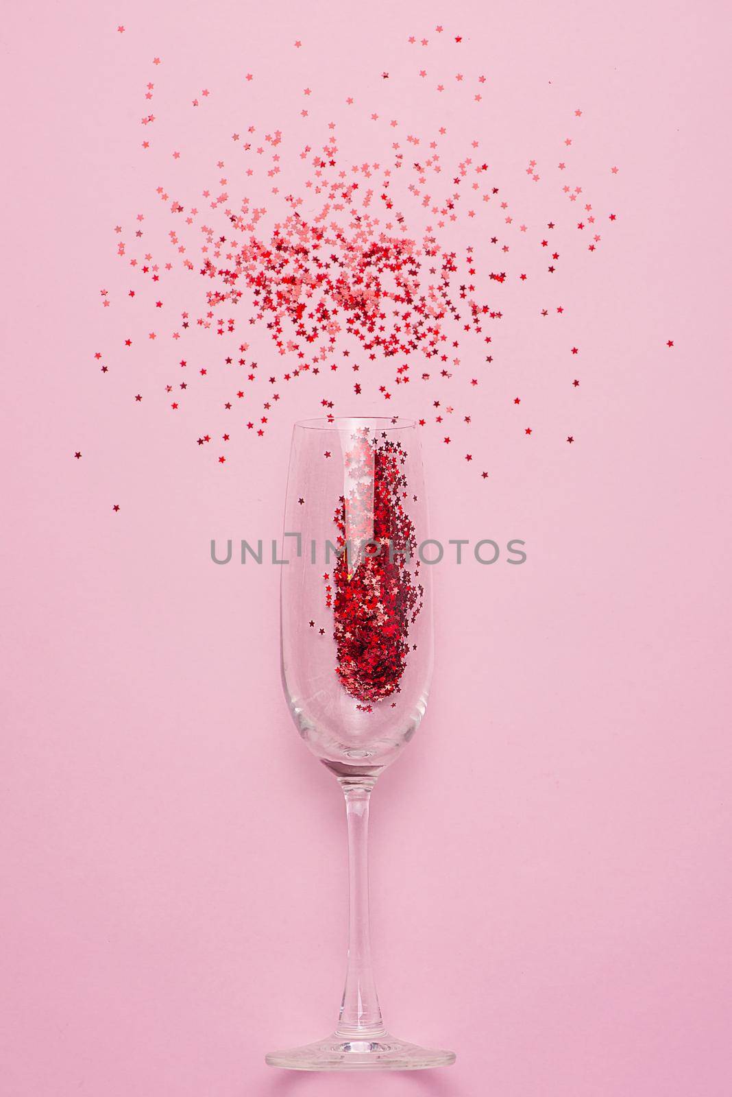 Flat lay of Celebration. Champagne glass with colorful party streamers on pink background. by makidotvn