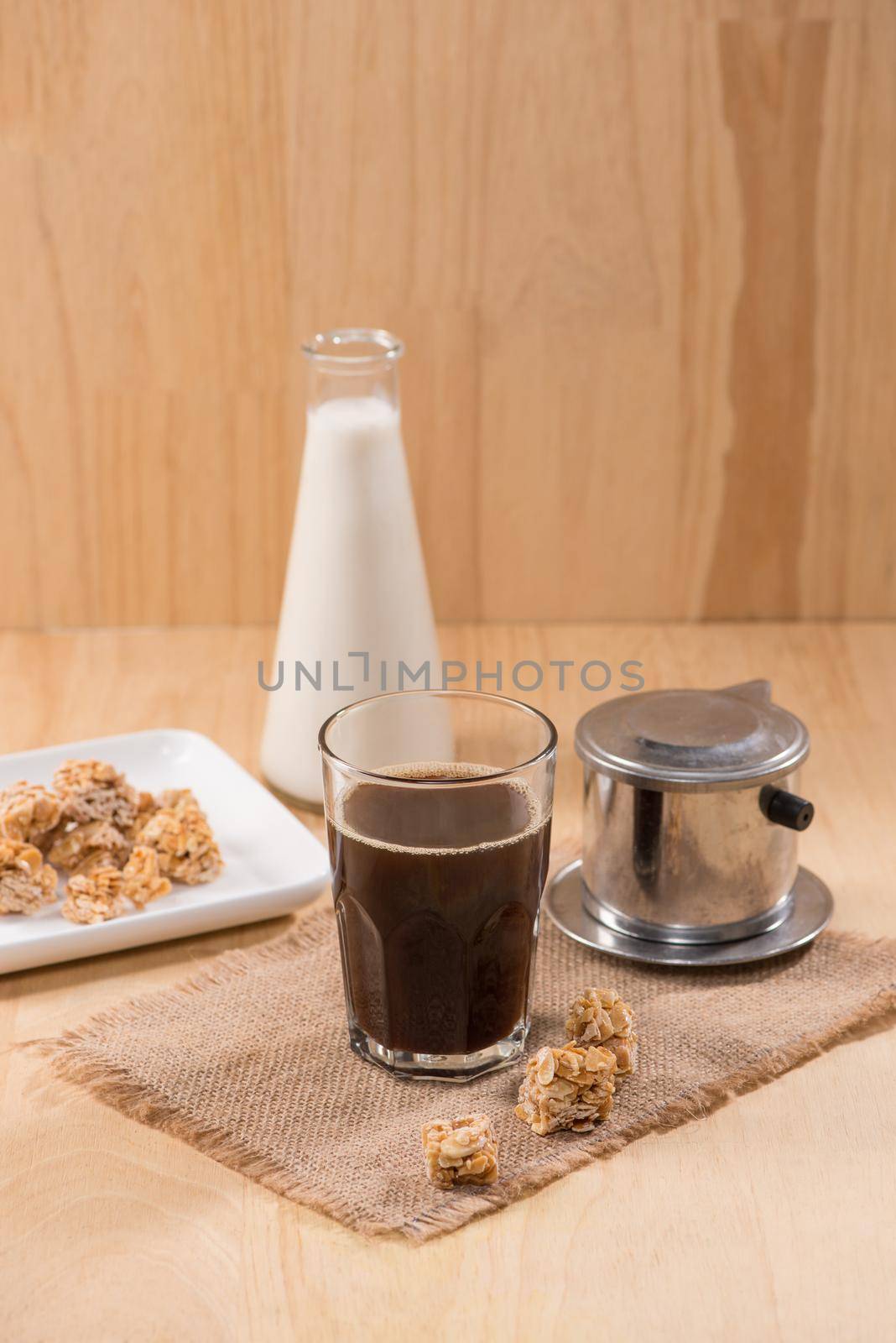 Glass of coffee with bottle of milk on a wooden table. by makidotvn