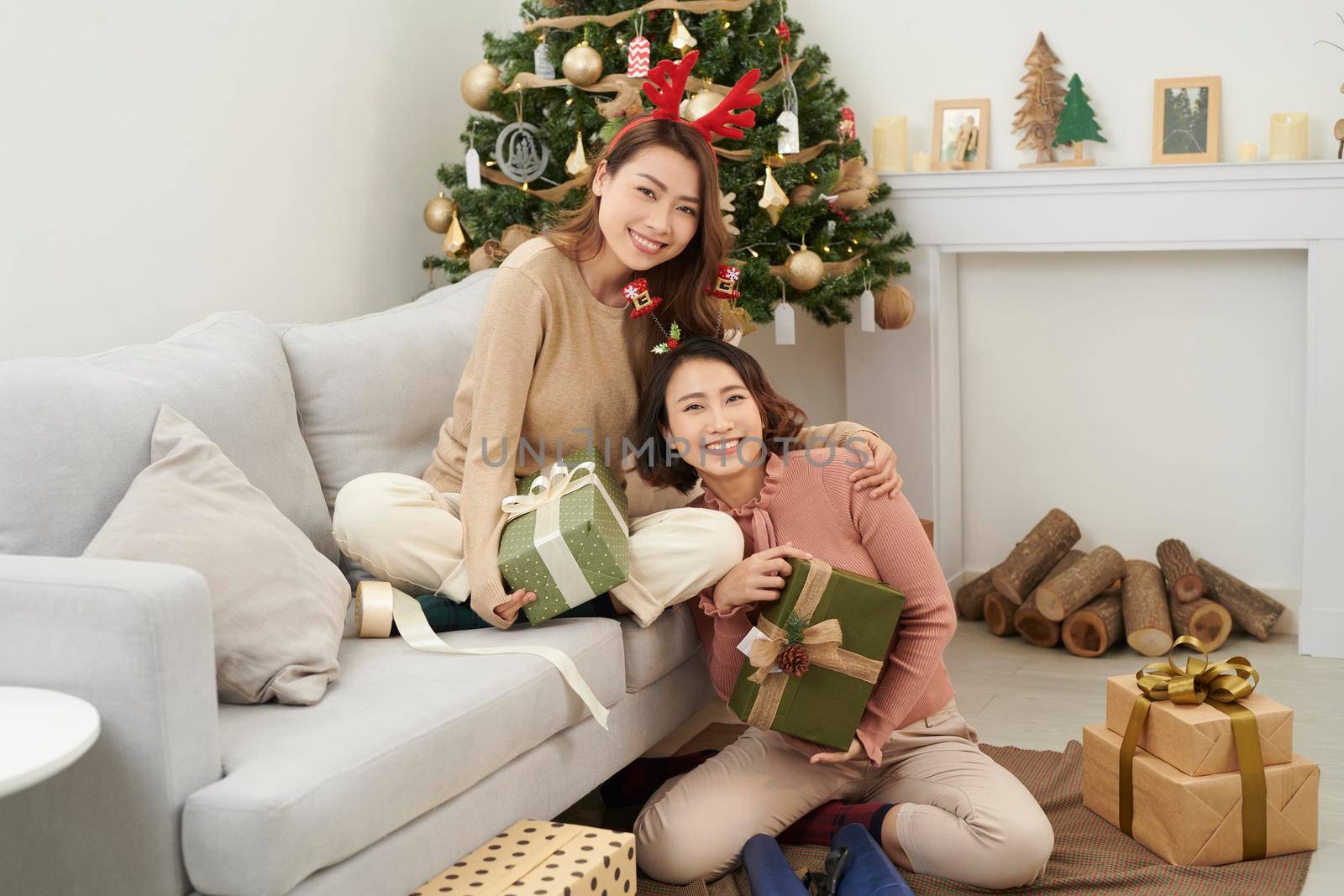 girl best friends celebrating christmas together. young ladies exchanging gifts at home and feel thankful hugging. love friendship on xmas concept.