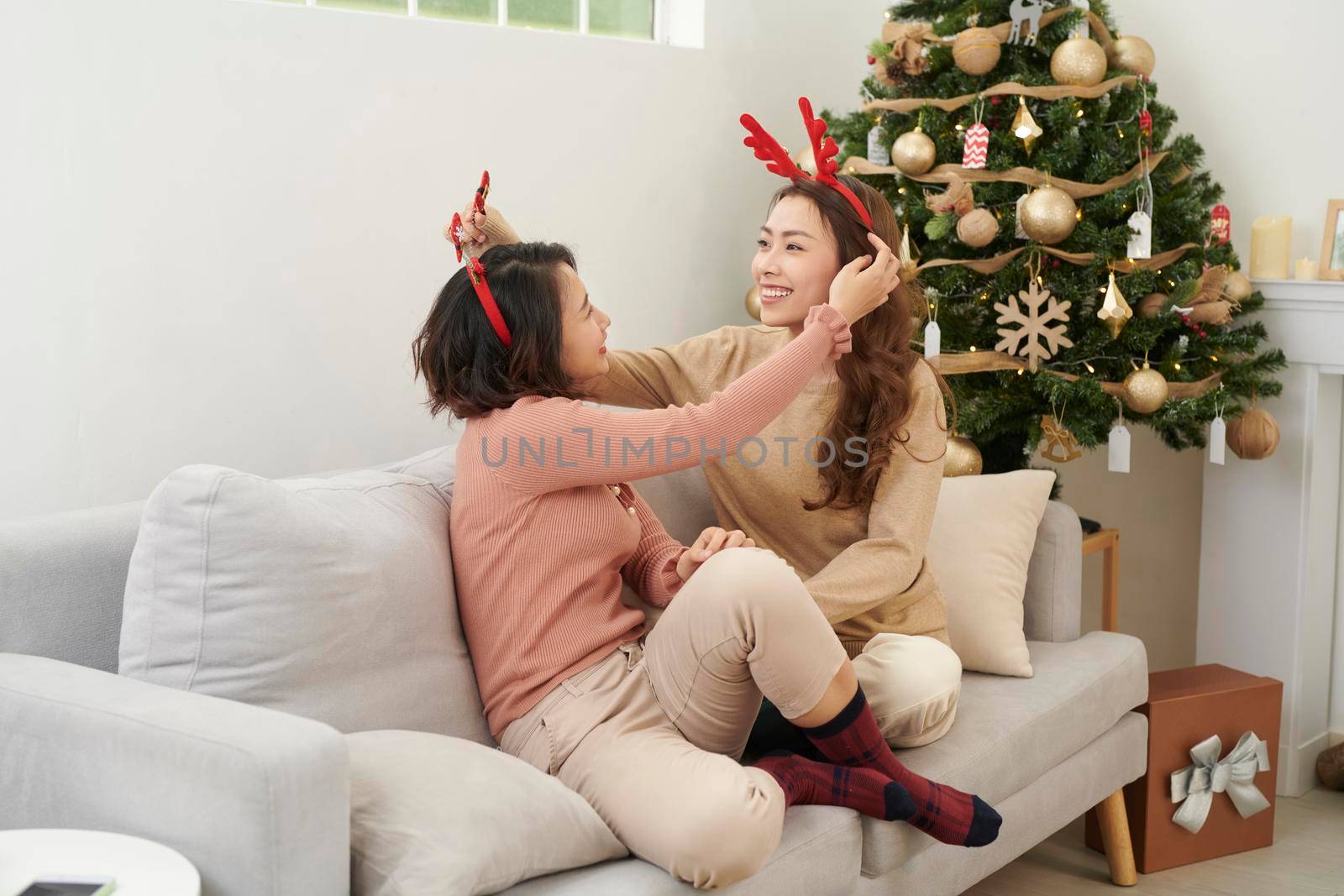 Friends cuddling on christmas day sitting on a couch in the living room at home