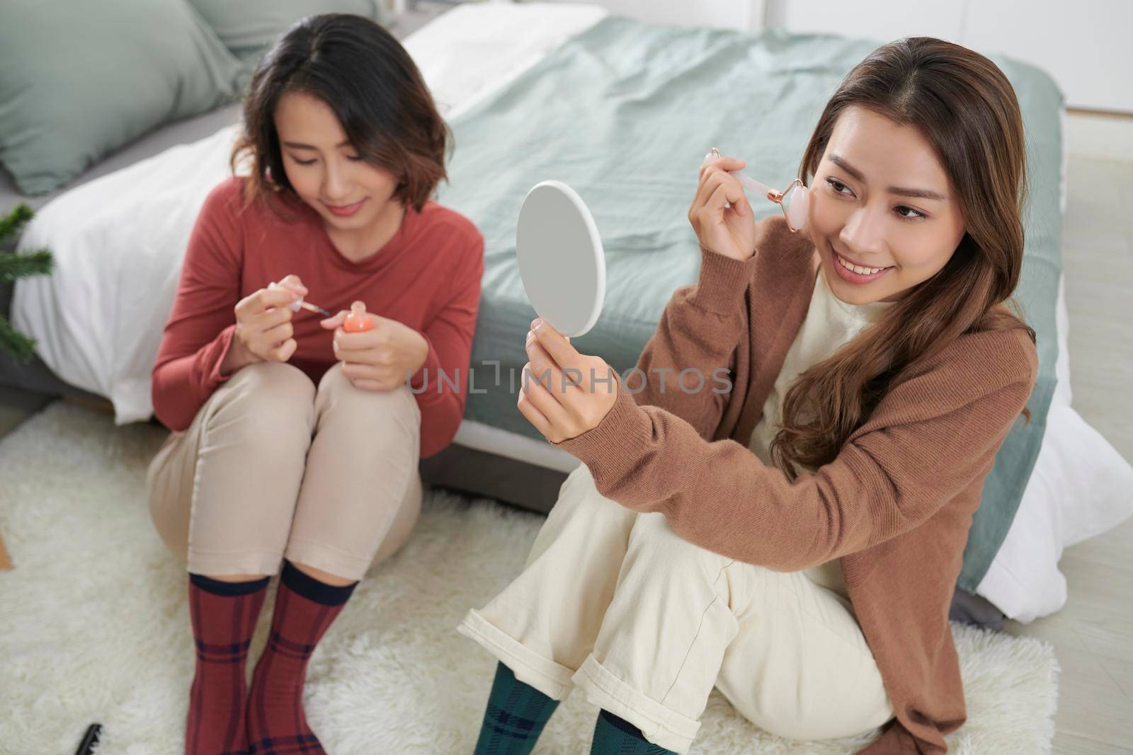 Two women together on a care treatment with face rollers for skin lifting. by makidotvn