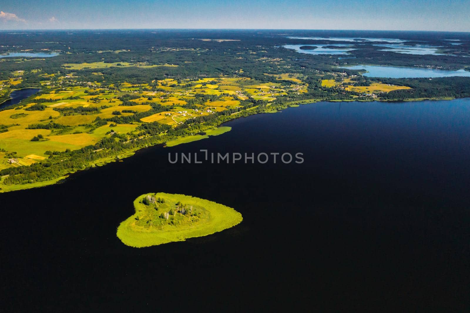 Love island on a lake in Europe, a Green heart-shaped Island on a dark lake with a sparkle from the sun by Lobachad