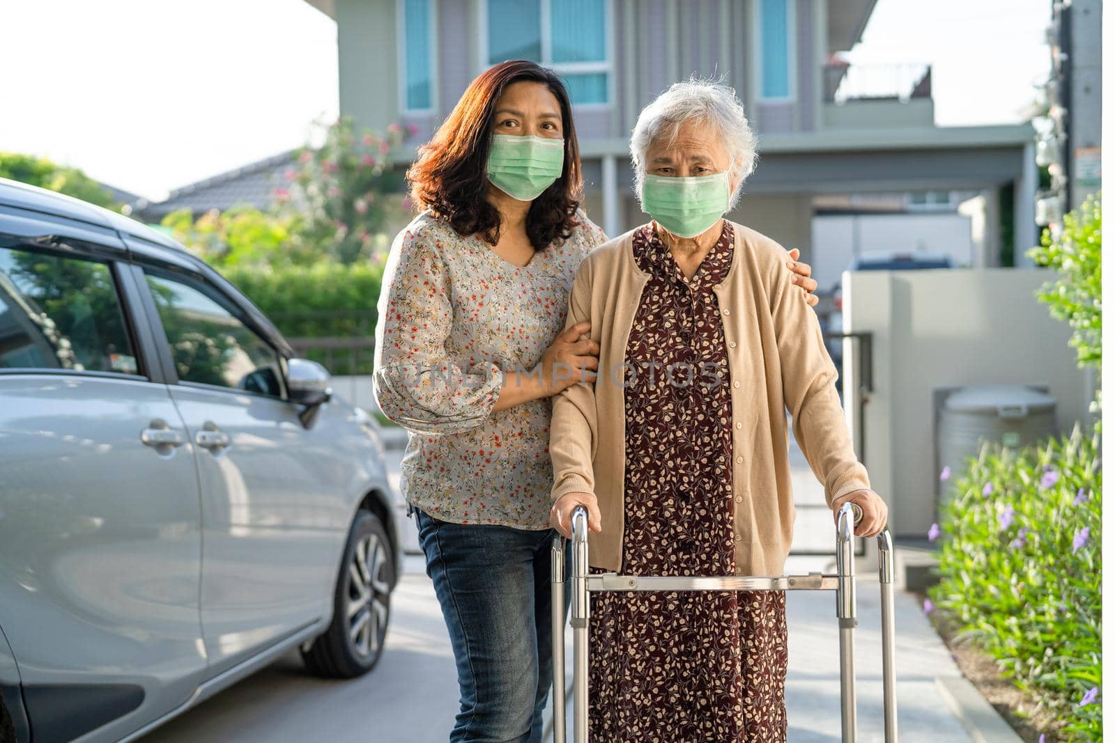 Asian senior or elderly old lady woman walk with walker and wearing a face mask for protect safety infection Covid-19 Coronavirus. by pamai