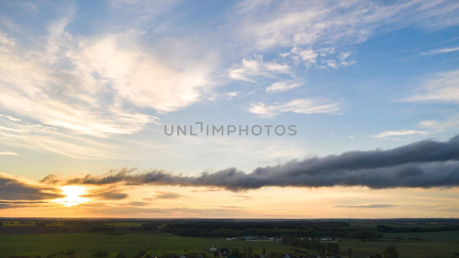 Green meadow under a blue sunset sky with clouds.