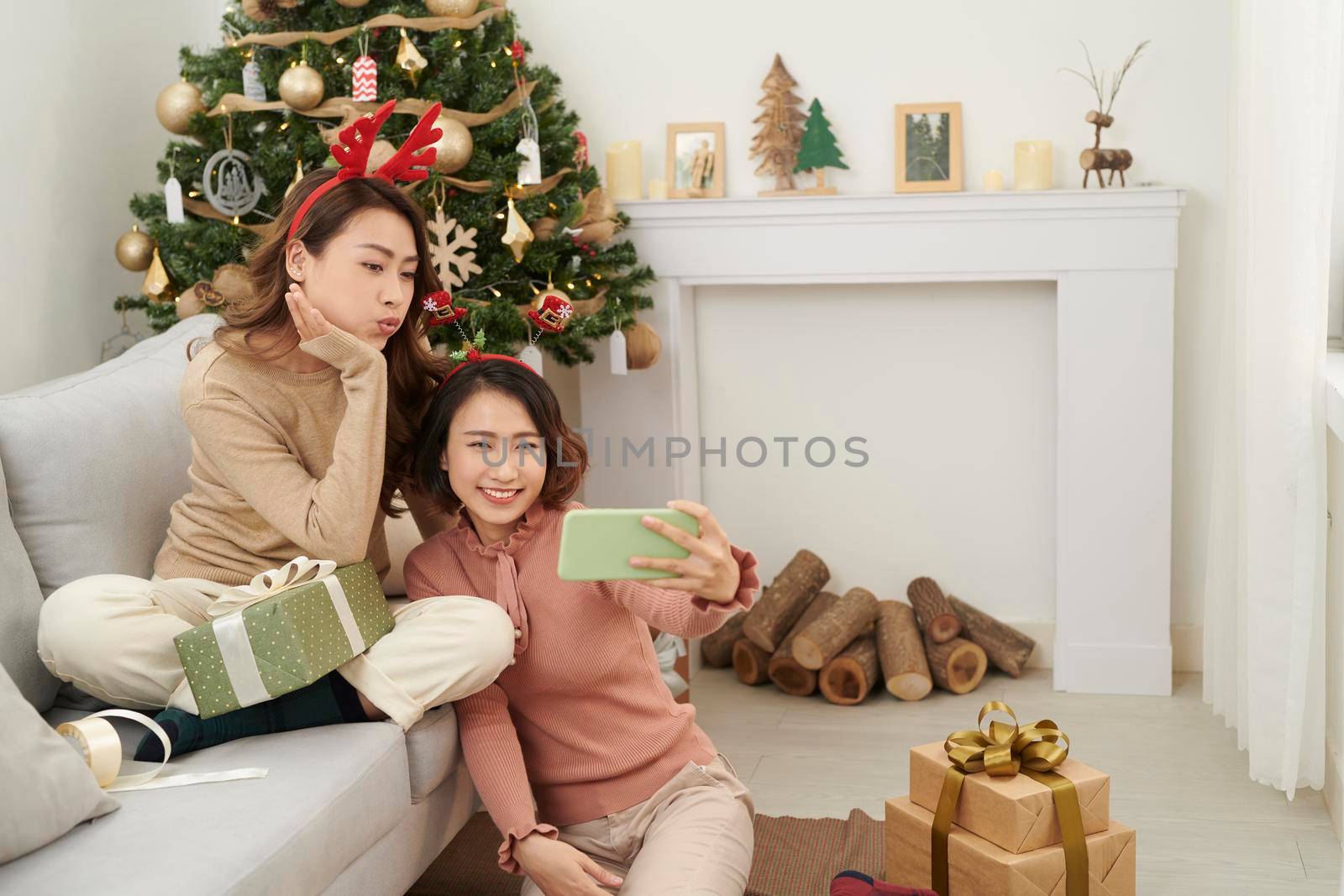 cute christmas girls showing presents to the cellphone friends. by makidotvn