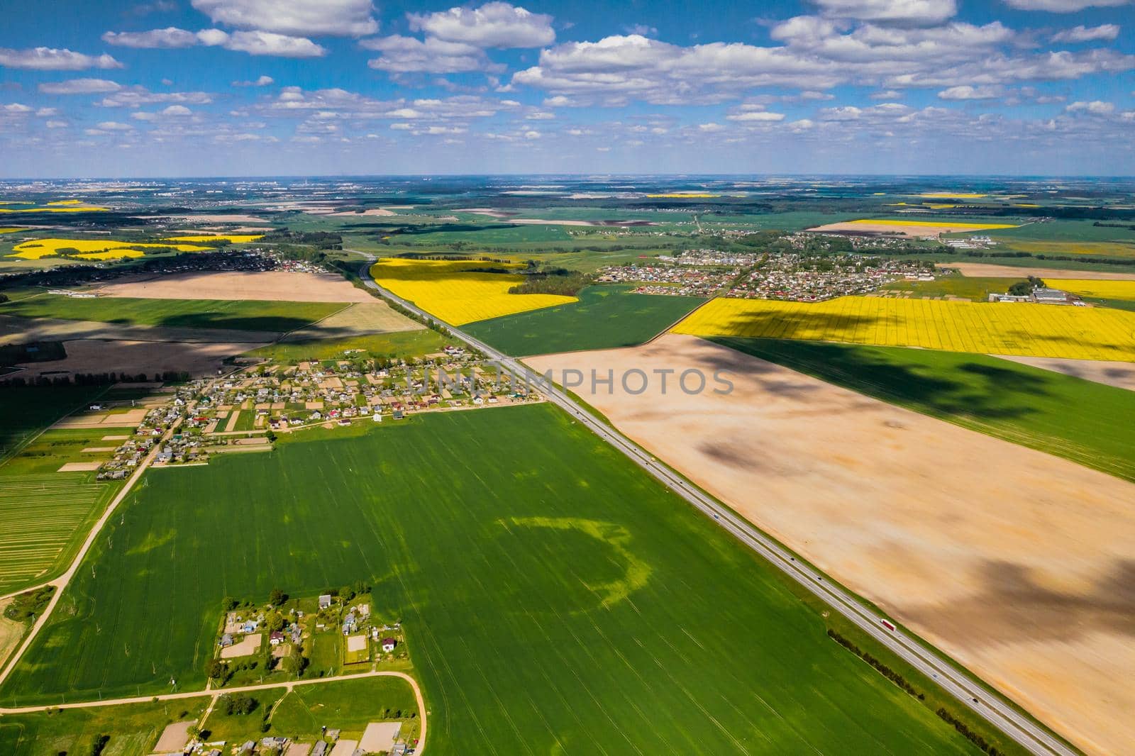 top view of a sown green field and a small village in Belarus. Agricultural fields in the village.Spring sowing in a small village.