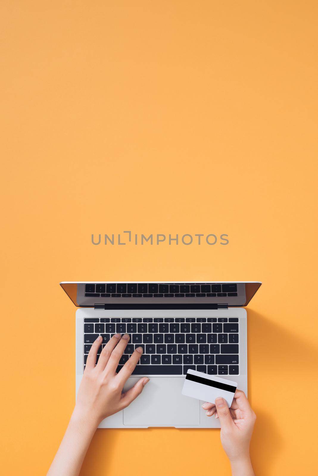 Top view of a woman shopping online using laptop with credit card