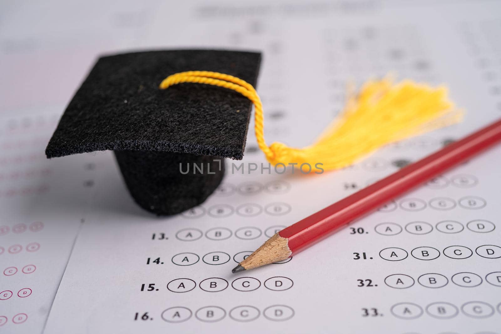 Graduation gap hat and pencil on answer sheet background, Education study testing learning teach concept. by pamai