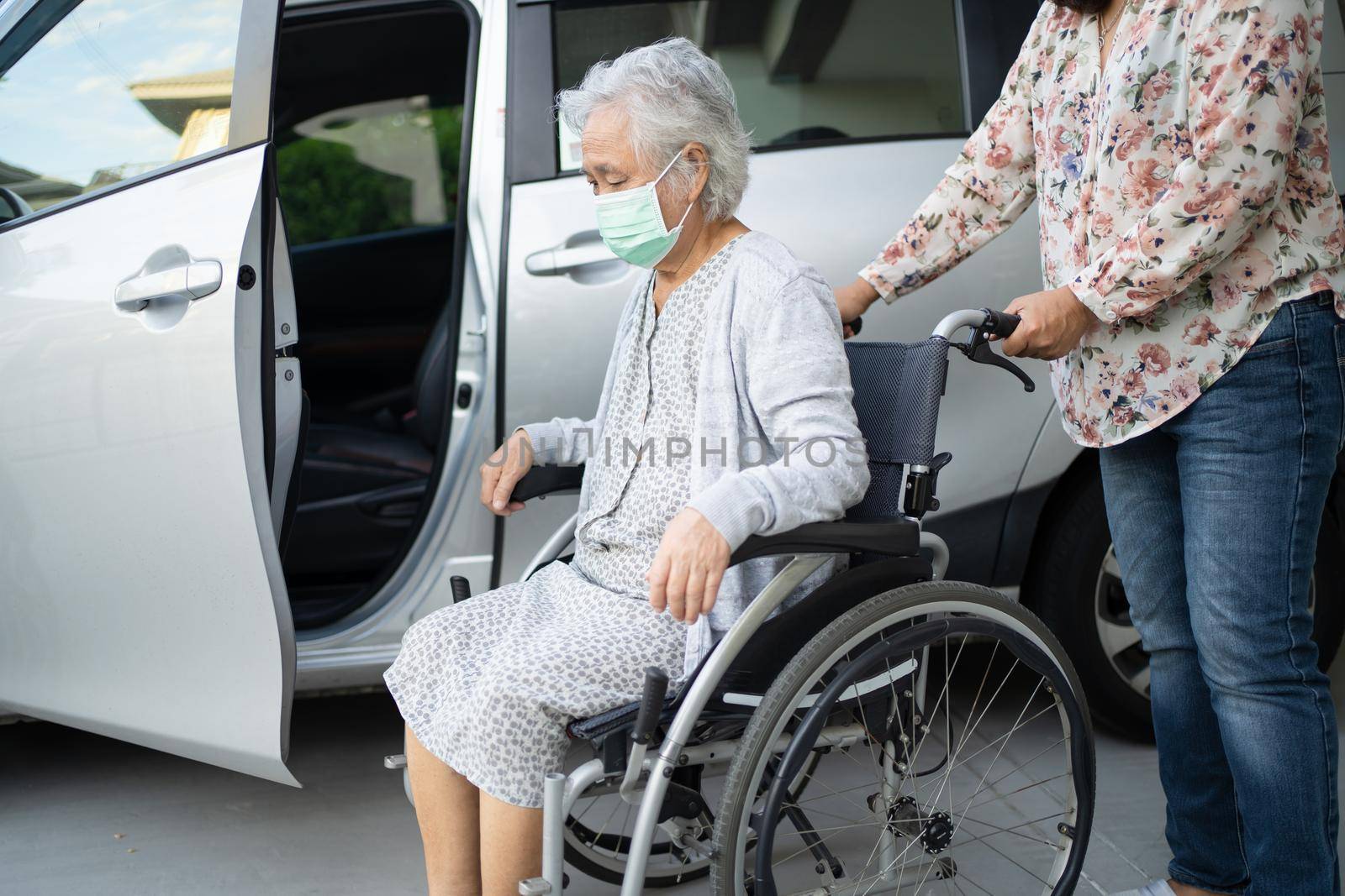 Help and support asian senior or elderly old lady woman patient sitting on wheelchair prepare get to her car, healthy strong medical concept. by pamai