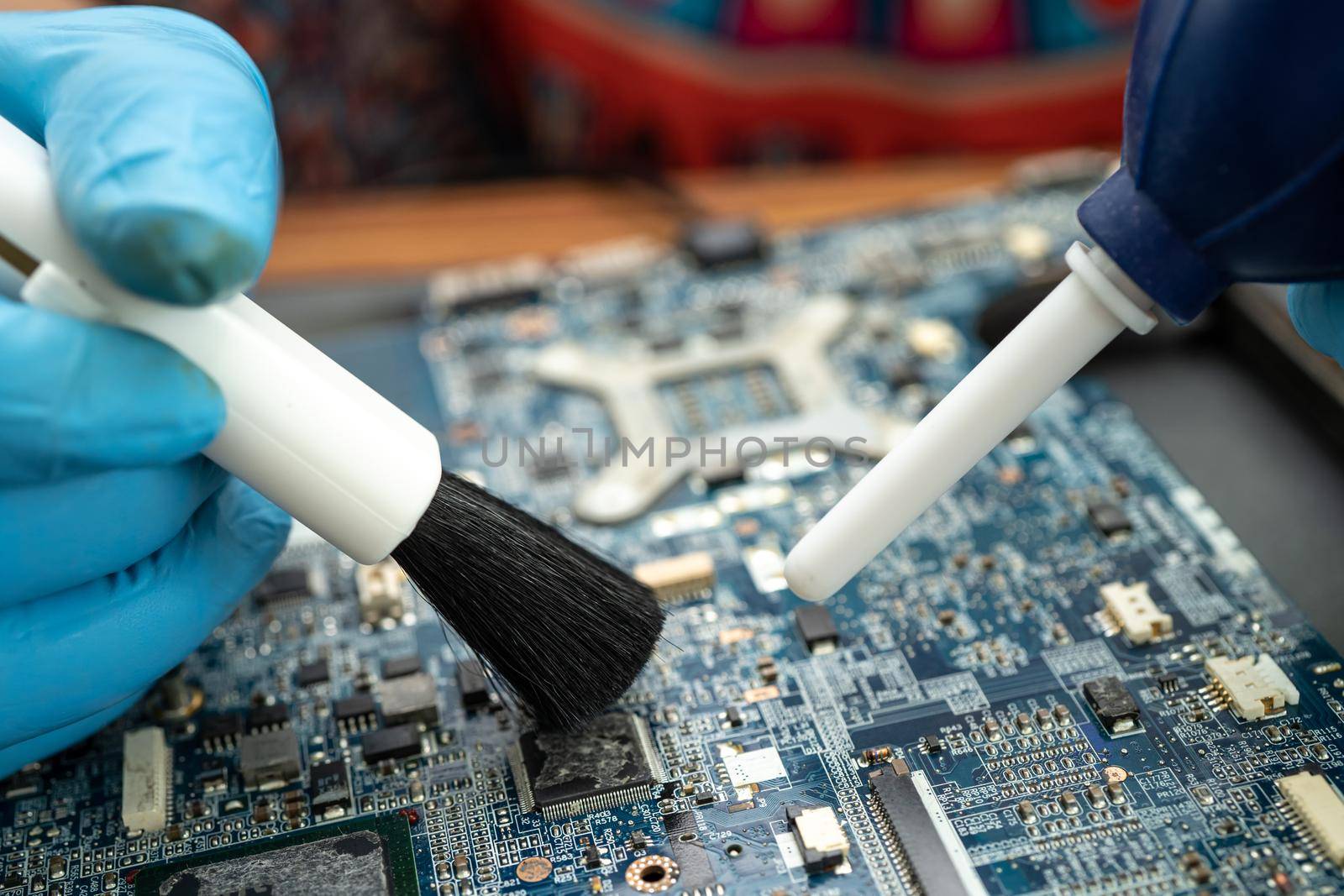 Technician use brush and air blower ball to clean dust in circuit board computer. Repair upgrade and maintenance technology.