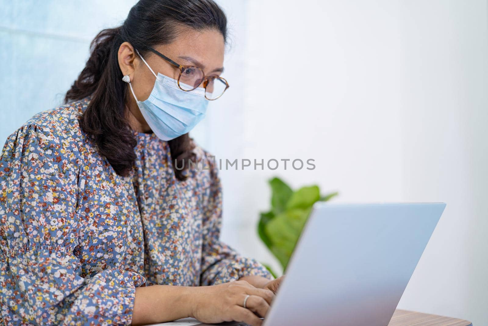 Asian lady businesswoman wearing mask for protect coronavirus to work from home communicate by conference video call on laptop, stay at home.