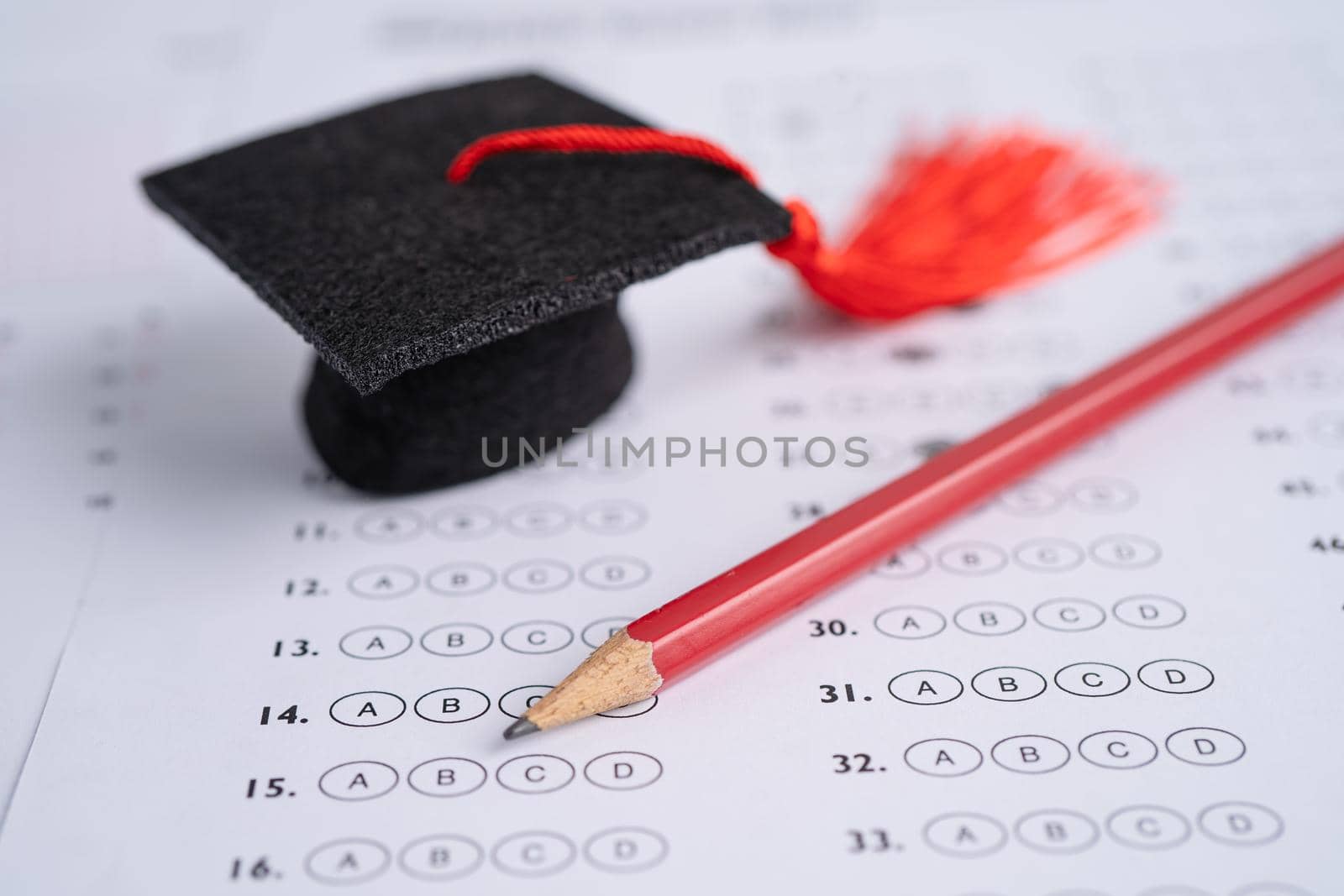 Graduation gap hat and pencil on answer sheet background, Education study testing learning teach concept. by pamai