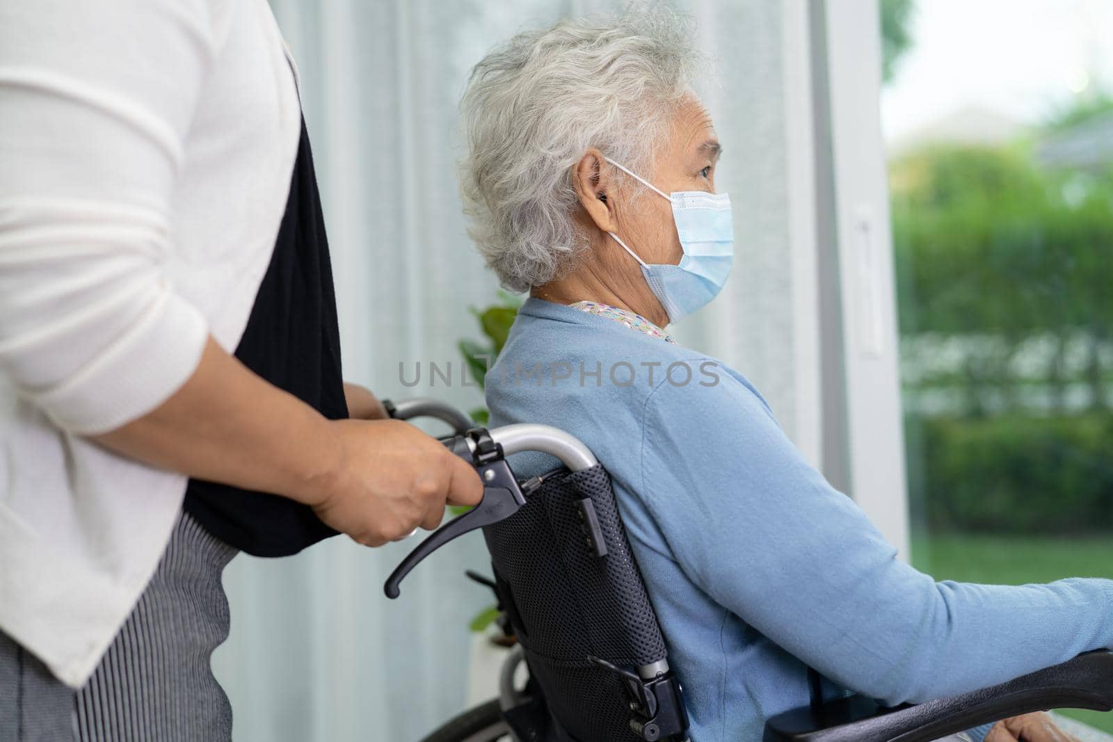 Help Asian senior or elderly old lady woman sitting on wheelchair and wearing a face mask for protect safety infection Covid-19 Coronavirus. by pamai
