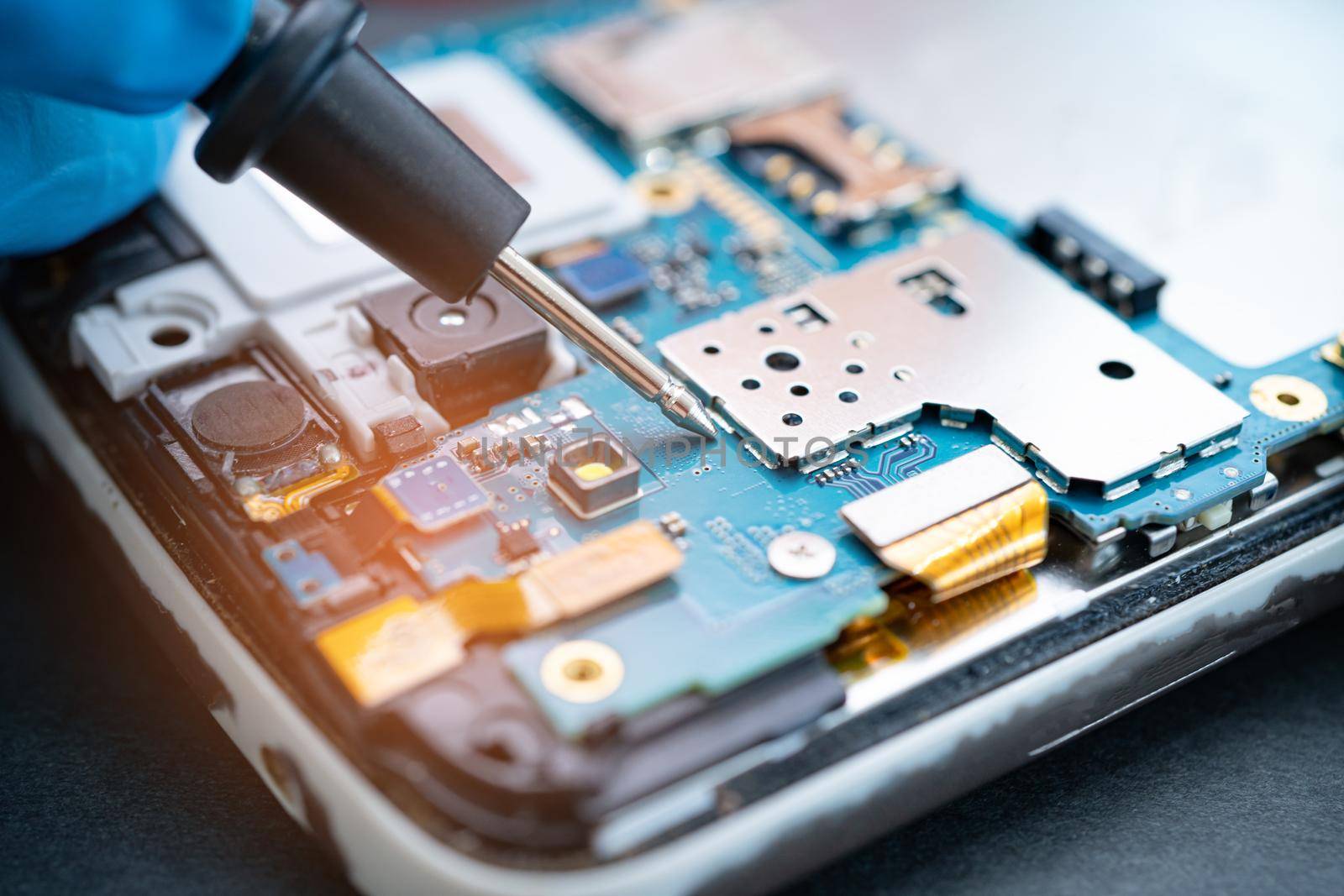 Technician repairing inside of mobile phone by soldering iron. Integrated Circuit. the concept of data, hardware, technology.