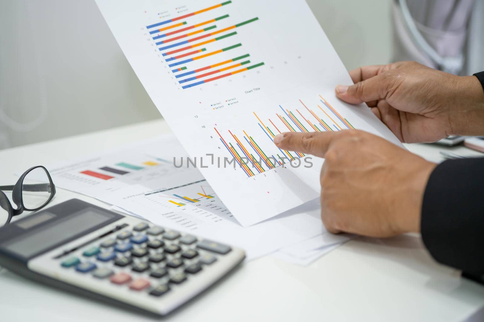 Asian accountant working and analyzing financial reports project accounting with chart graph and calculator in modern office, finance and business concept. by pamai