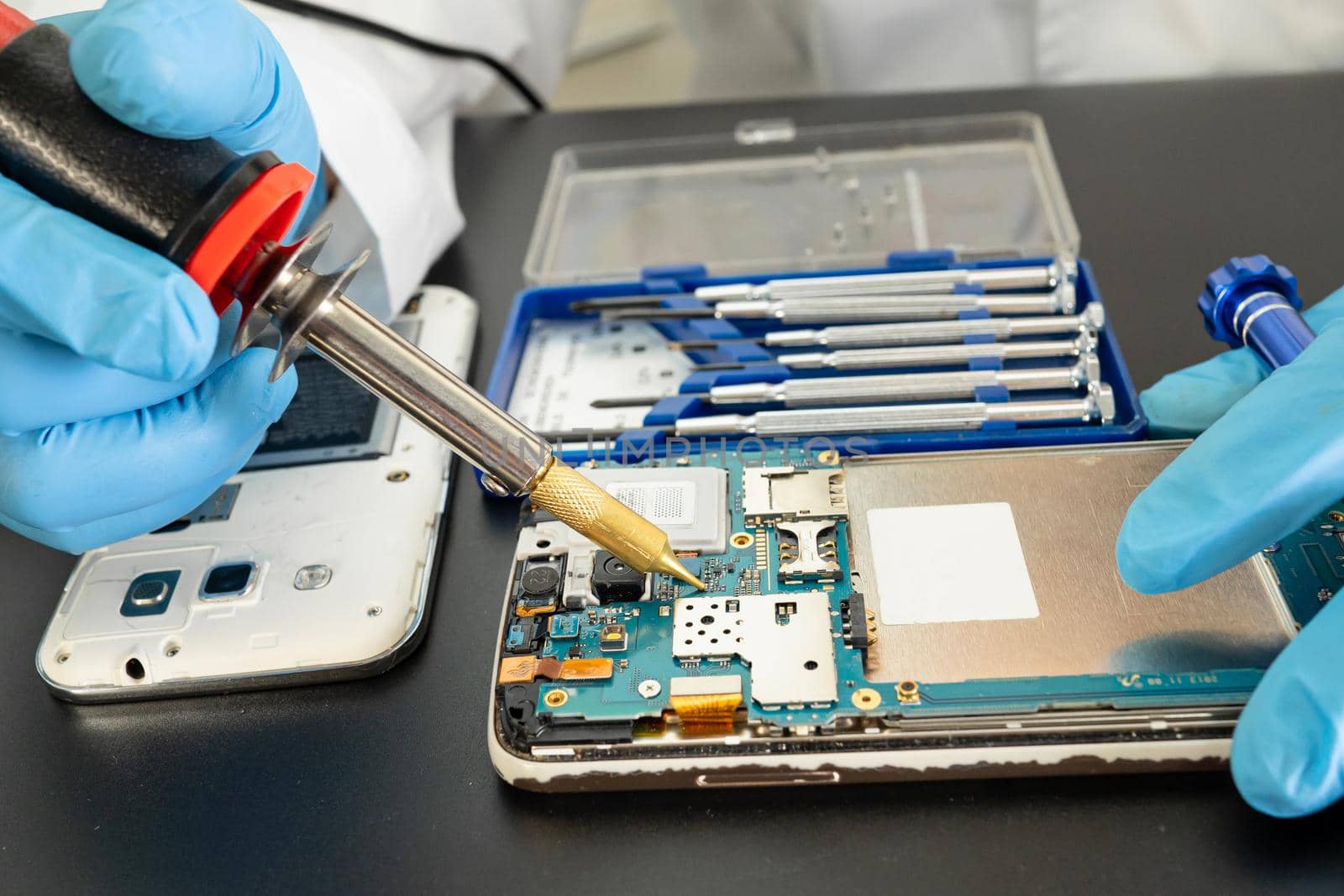 Technician repairing inside of mobile phone by soldering iron. Integrated Circuit. the concept of data, hardware, technology.